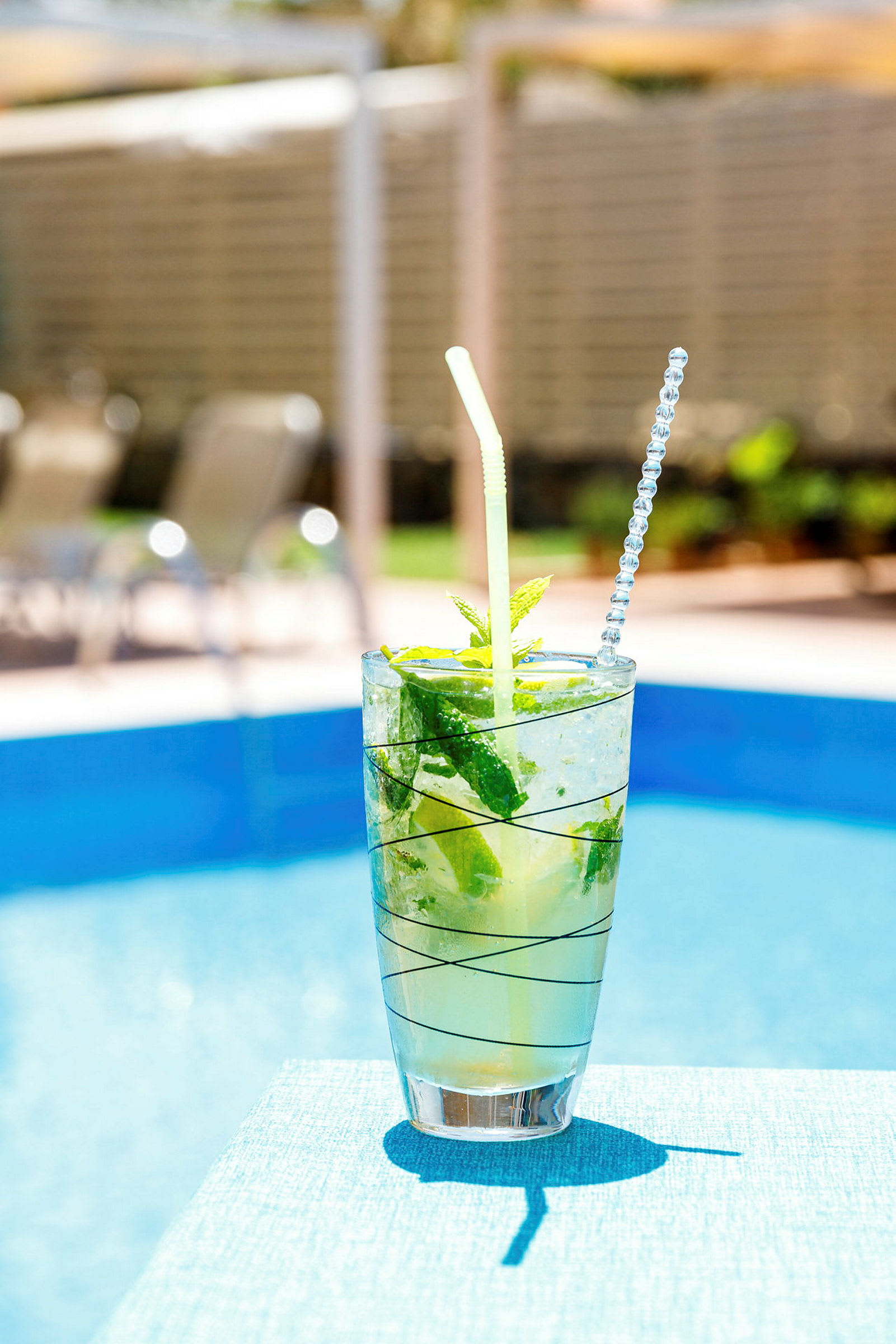 En glassdrink med is, mynte og lime ved et basseng. (AI-generert tekst)