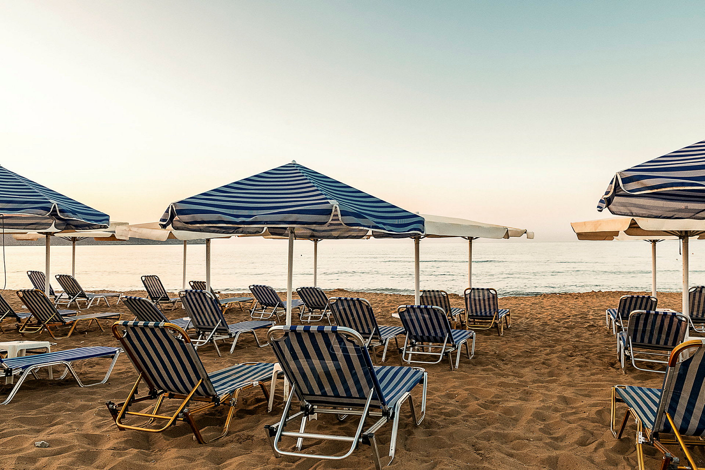 Solstoler og parasoller på en sandstrand ved havet. (AI-generert tekst)