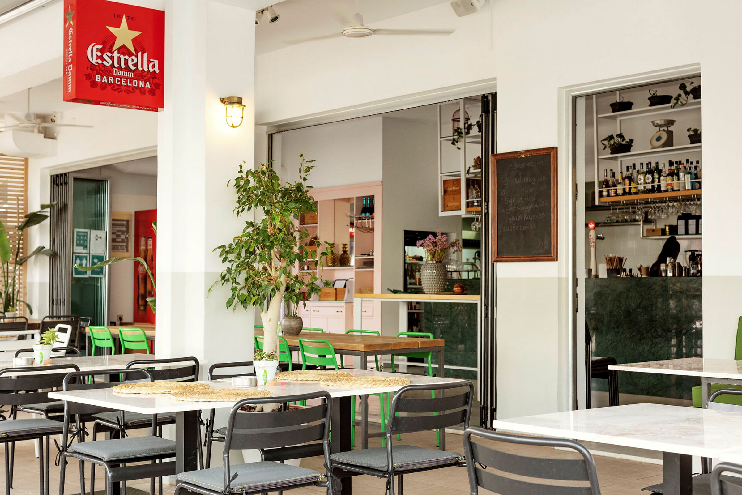 Uteservering med bord og stoler, med en åpen inngang til en moderne bar. (AI-generert tekst)