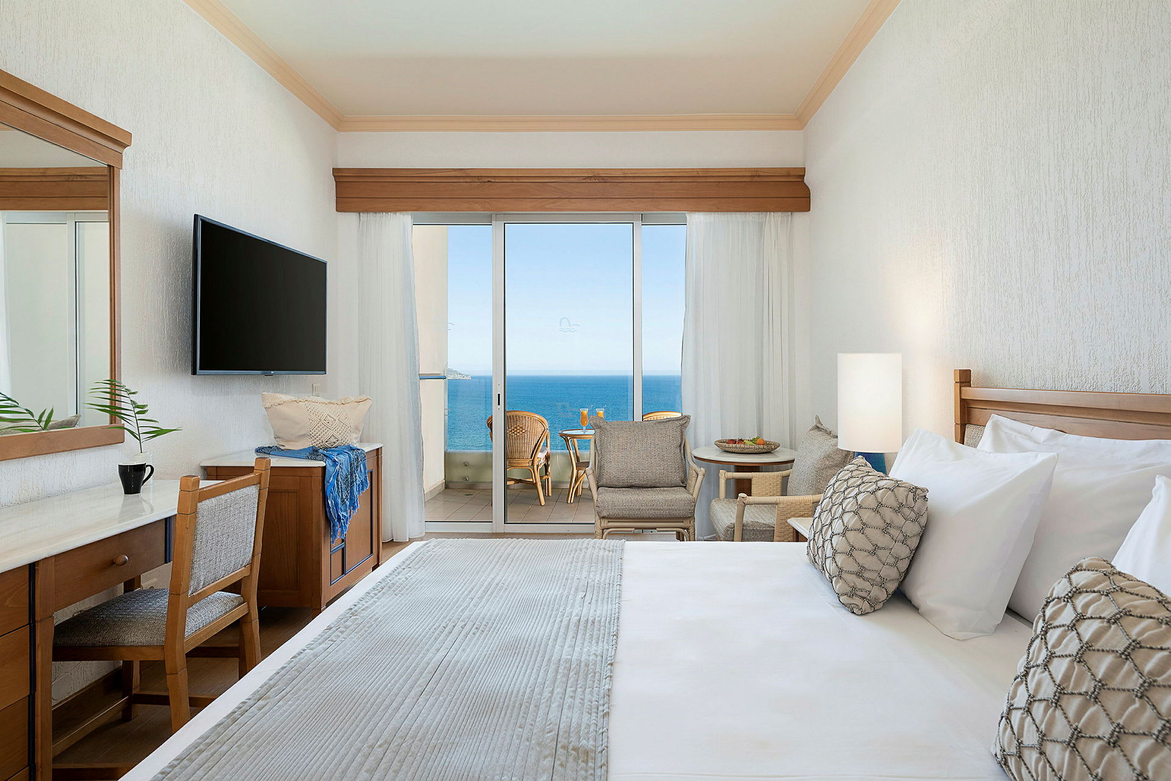 Hotellrom med utsikt mot havet gjennom store glassdører. (AI-generert tekst)