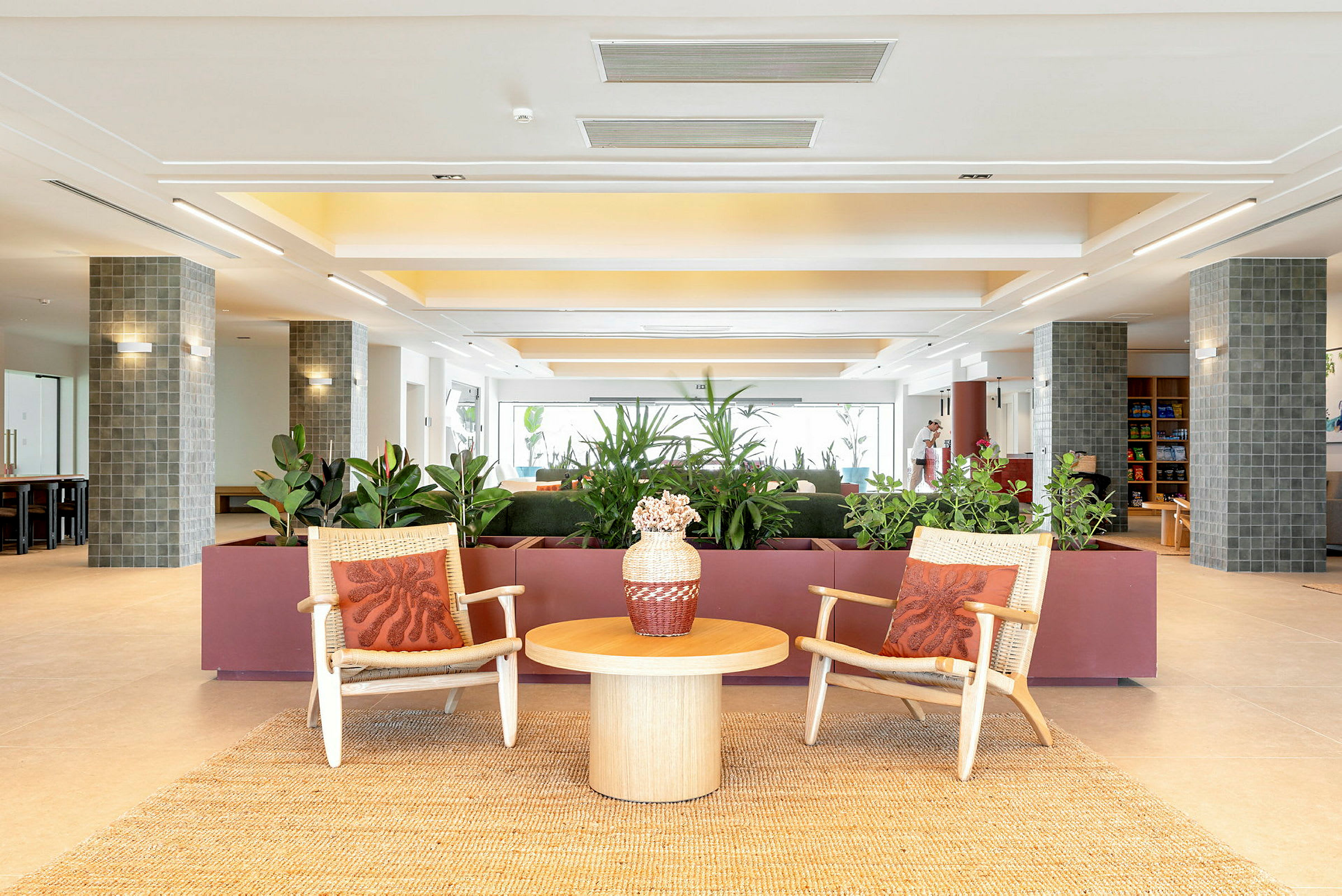 Bilde av en moderne hotellobby med to stoler, et bord og planter i bakgrunnen. (AI-generert tekst)