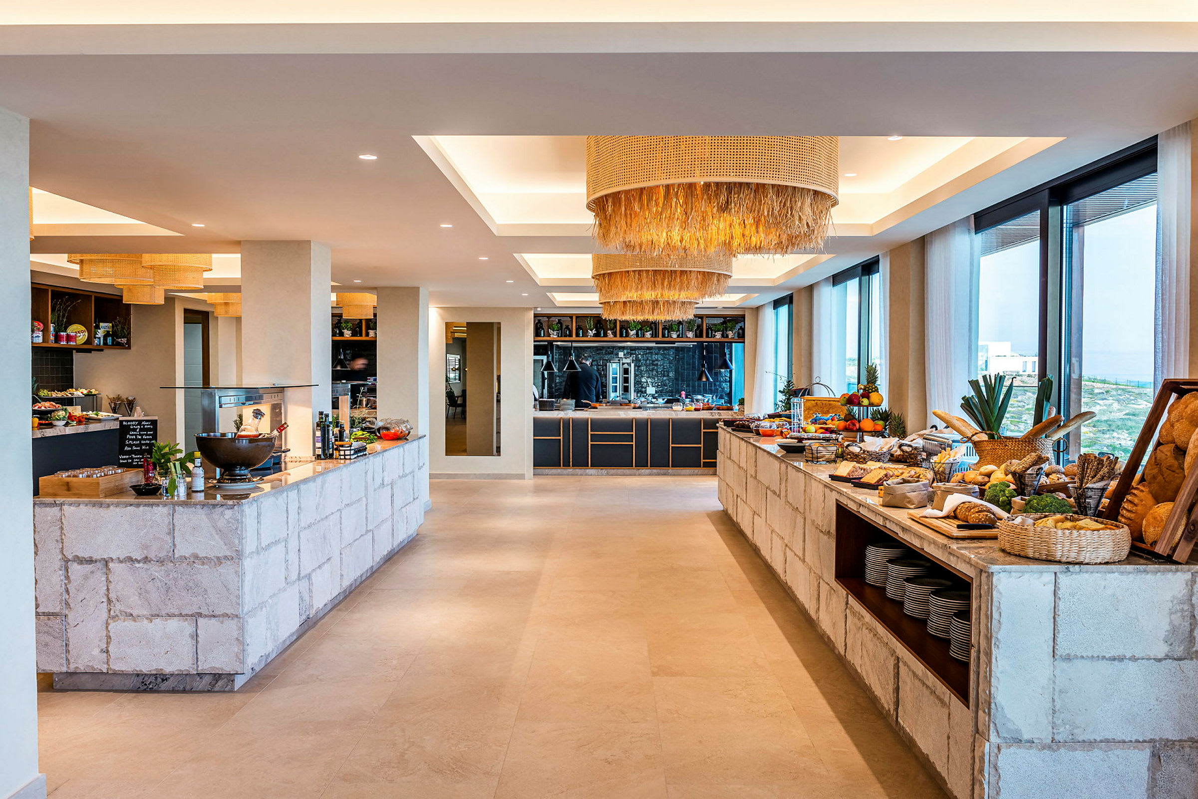 Interiør av en buffet med mat og drikke oppstilt på steinmurer, moderne lamper i taket og store vinduer med utsikt. (AI-generert tekst)