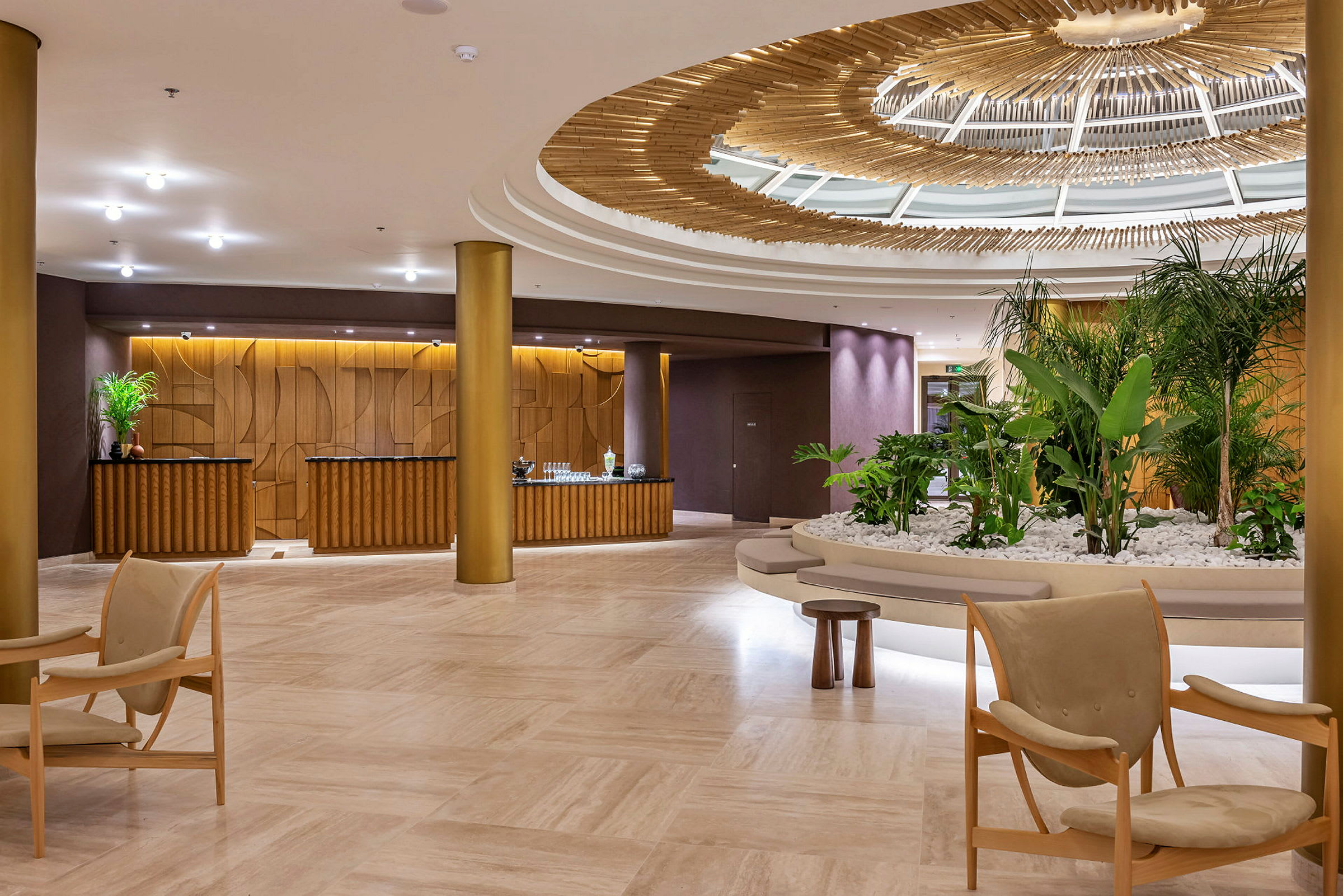Et hotellobbyområde med elegant interiør, inkludert grønne planter, sittemøbler og en dekorativ takstruktur. (AI-generert tekst)