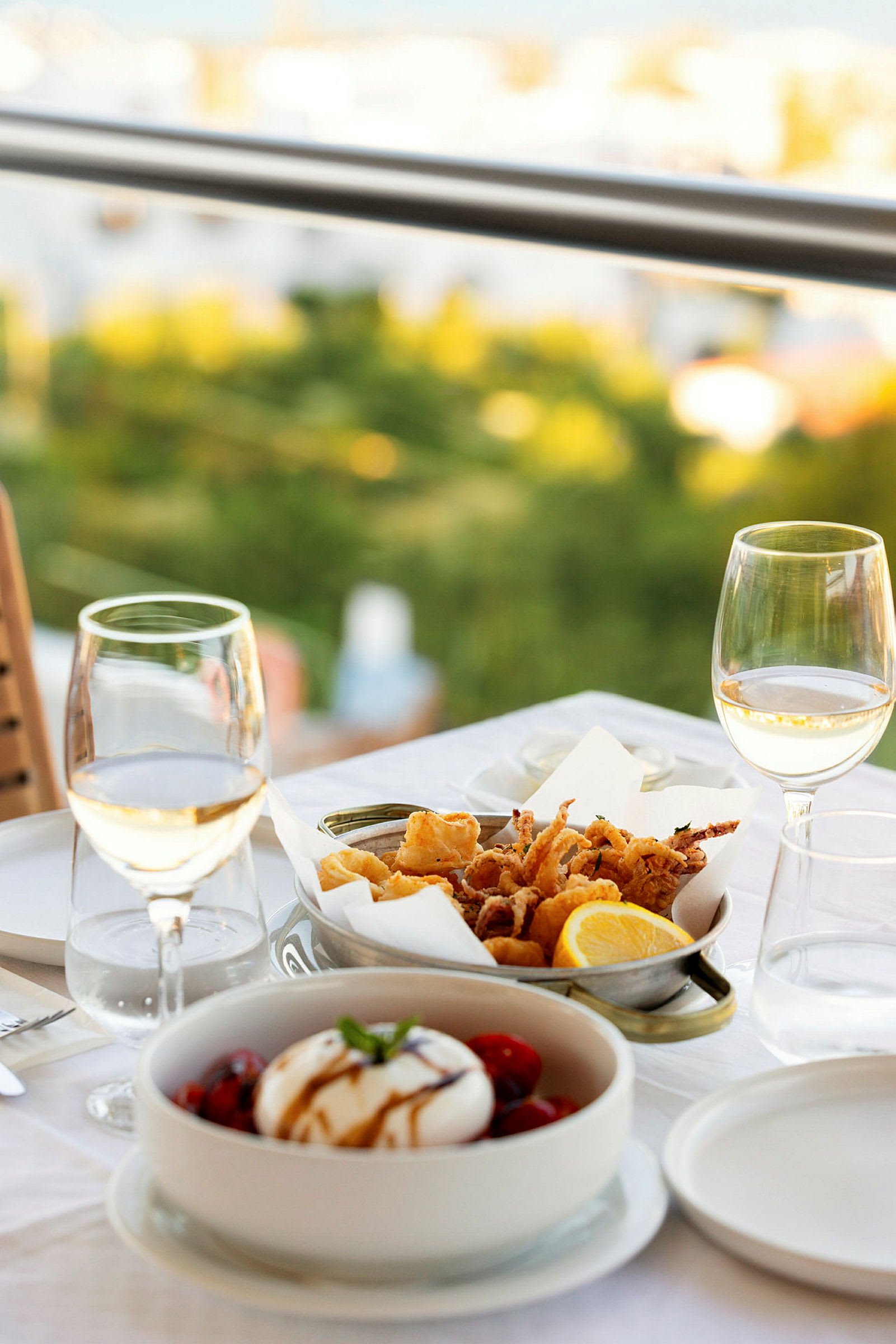 Et dekket bord med vin, salat og fritert sjømat. (AI-generert tekst)