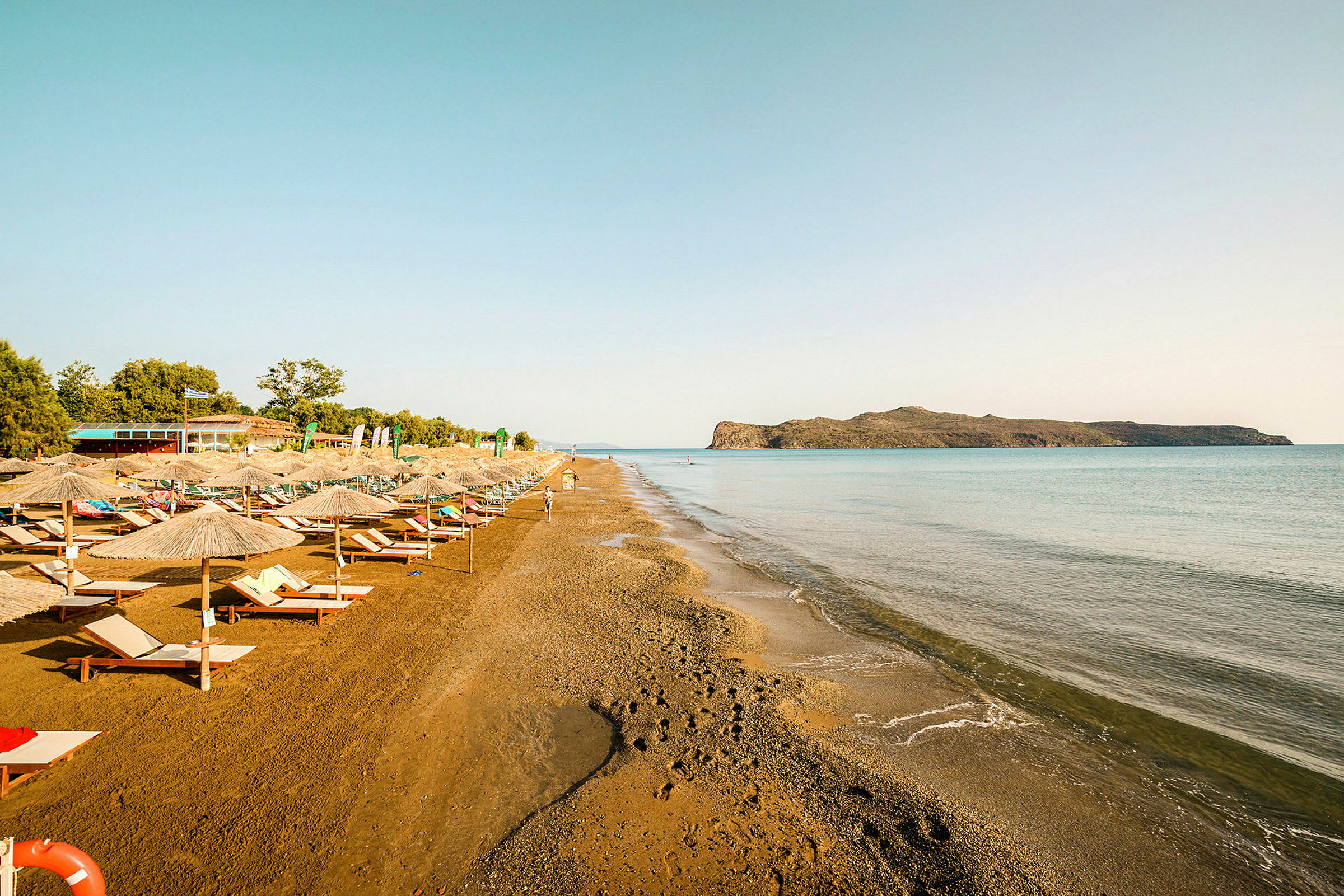 Strand med solsenger og parasoller langs vannet. (AI-generert tekst)