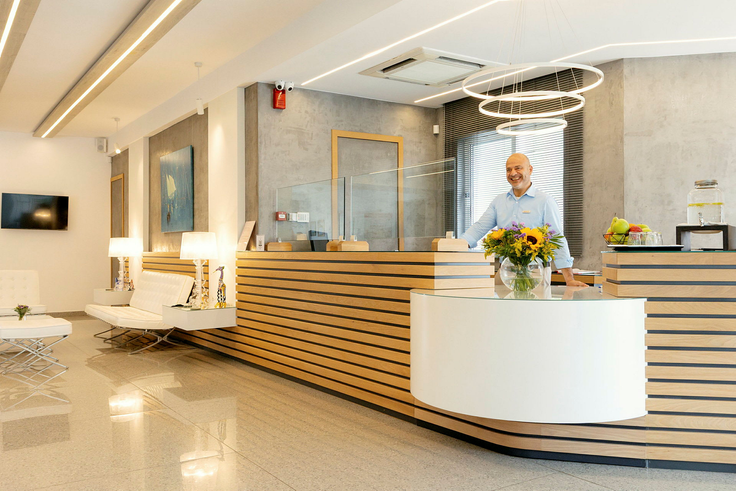 Hotellresepsjon med moderne innredning, blomster og personale ved skranken. (AI-generert tekst)
