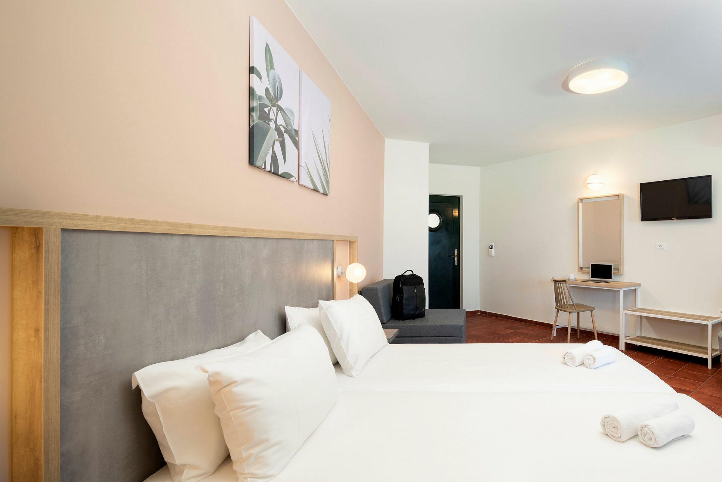 Hotellrom med dobbeltseng, sitteområde, skrivebord og TV. (AI-generert tekst)