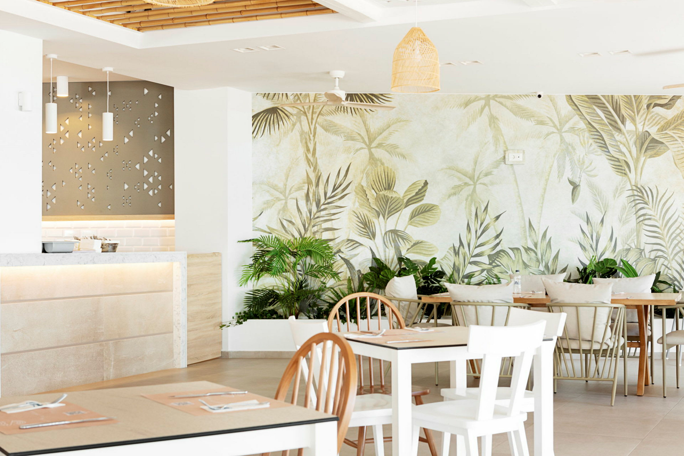 Interiør av en restaurant med lyse møbler og veggmaleri av tropiske blader. (AI-generert tekst)