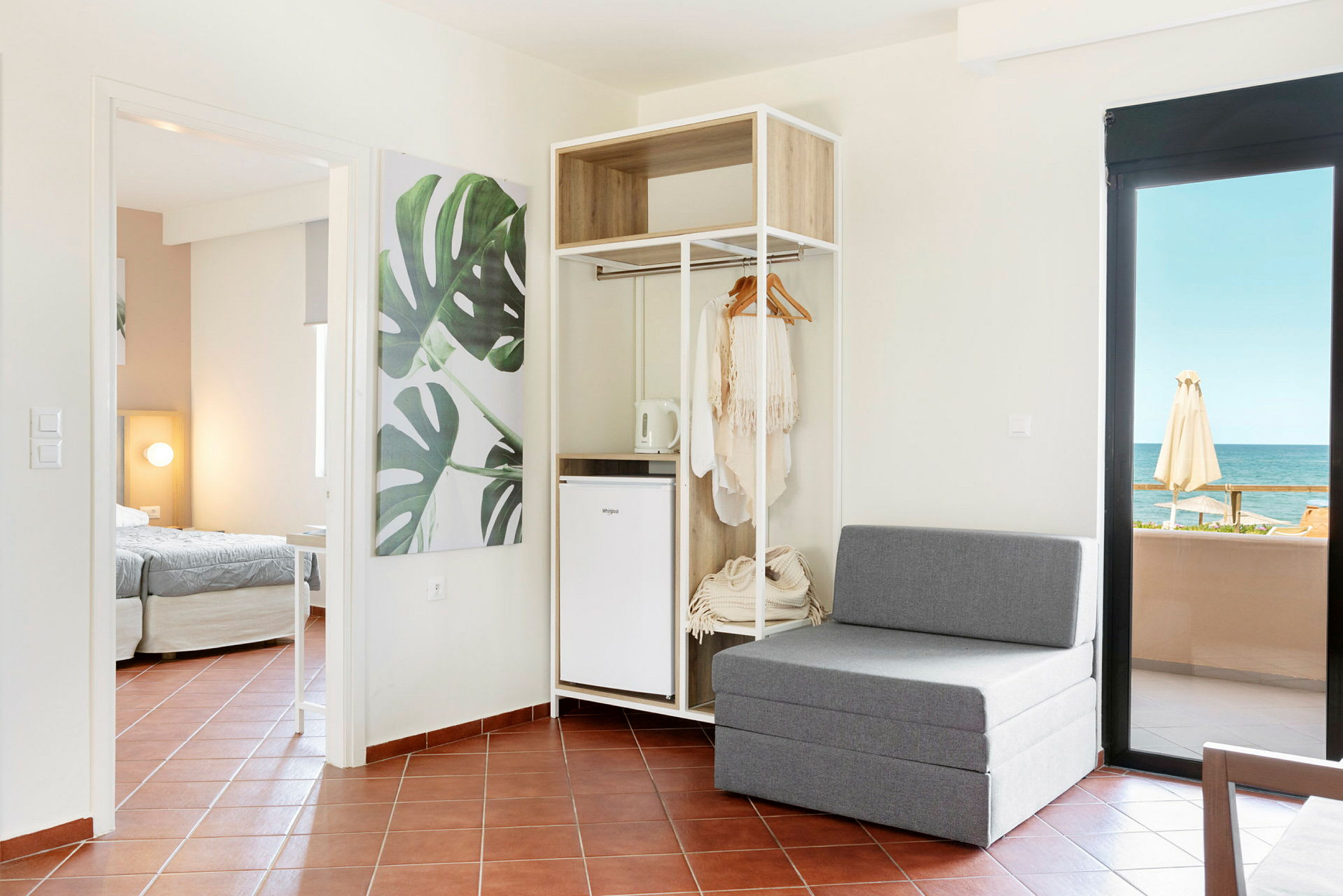 Moderne hotellrom med sittemøbler, åpen garderobe og havutsikt. (AI-generert tekst)