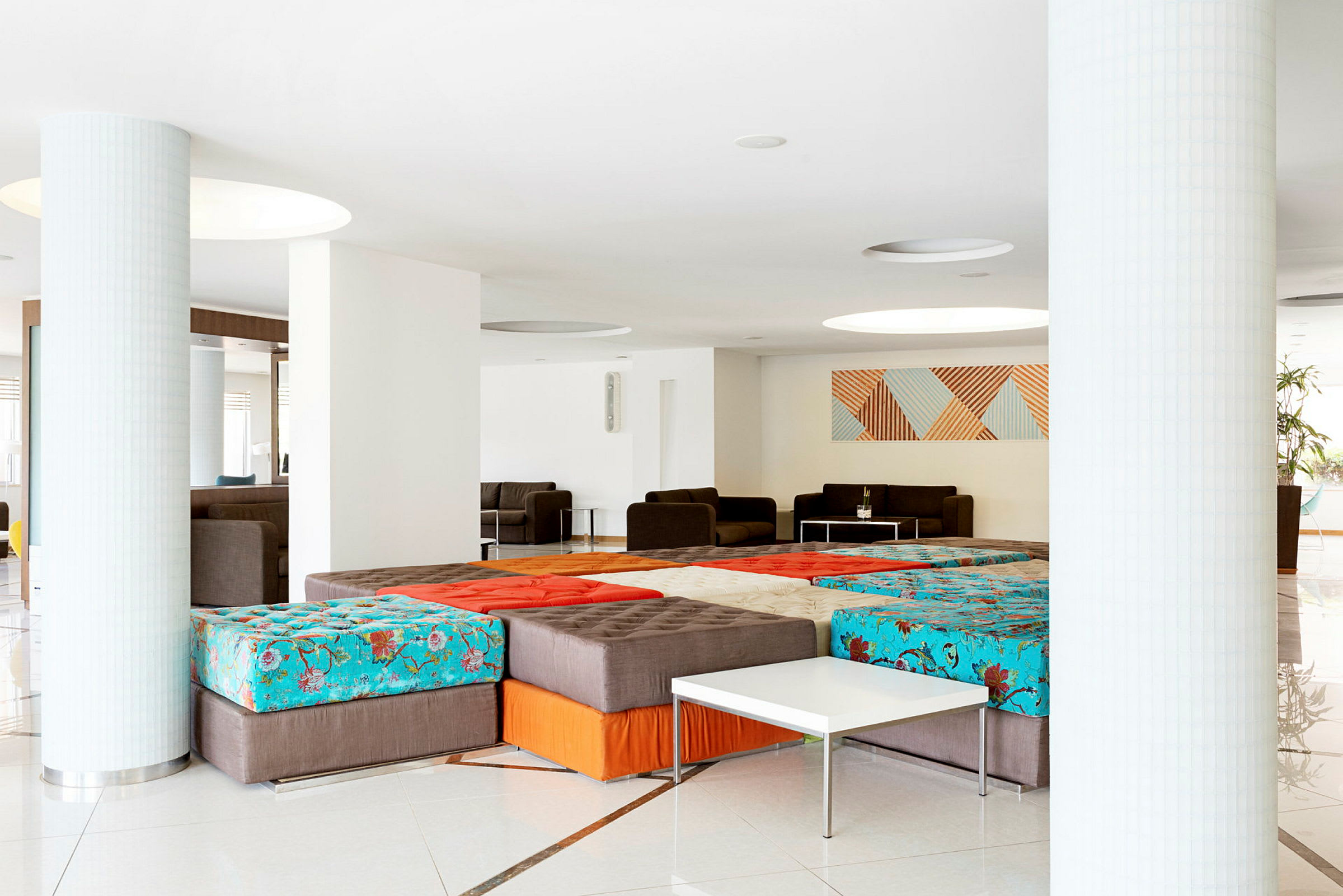 En åpen og lys lobby med sofagrupper og fargerike sittemøbler. (AI-generert tekst)