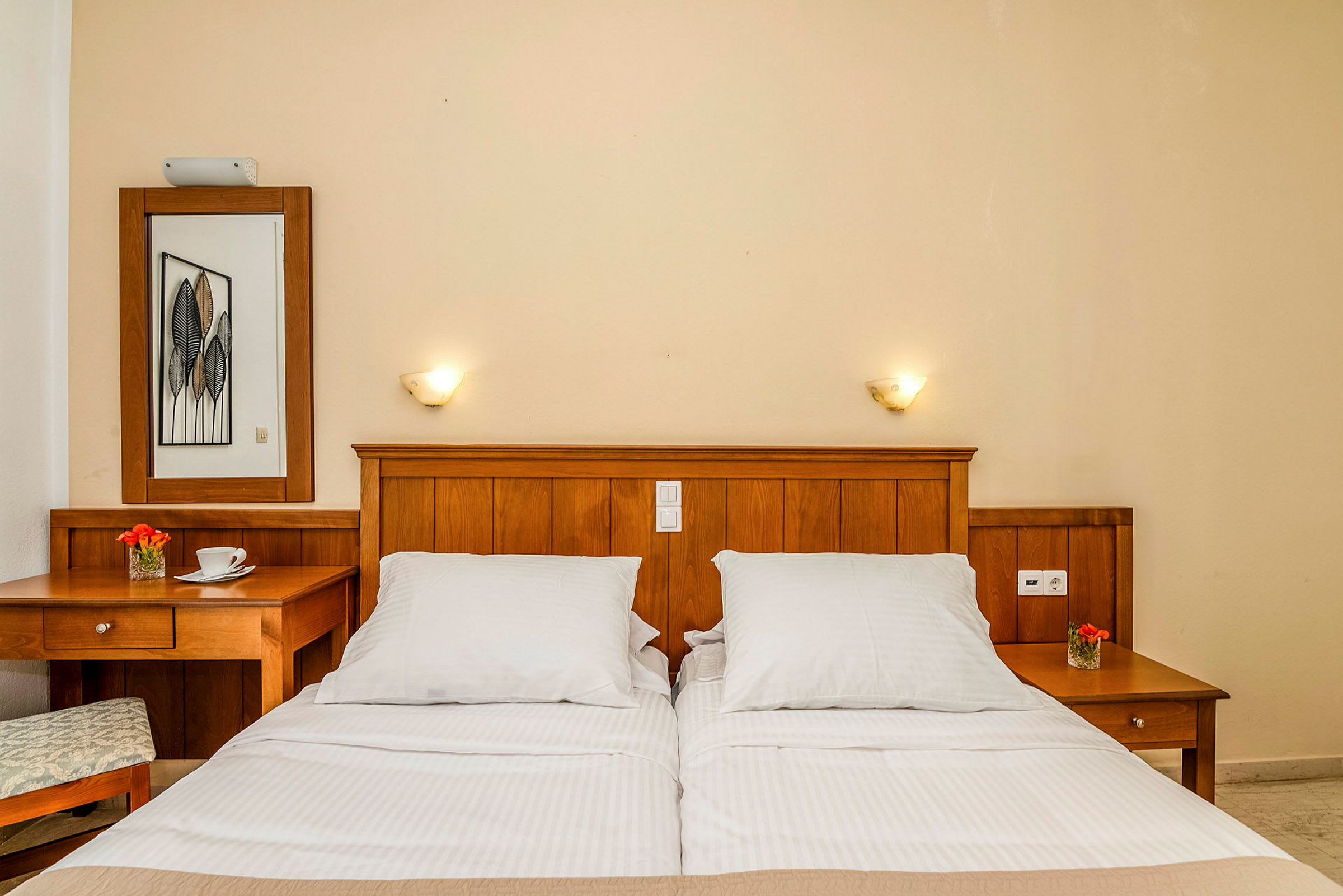 Hotellrom med dobbeltseng med trehodegjerde, nattbord og vegglamper. (AI-generert tekst)