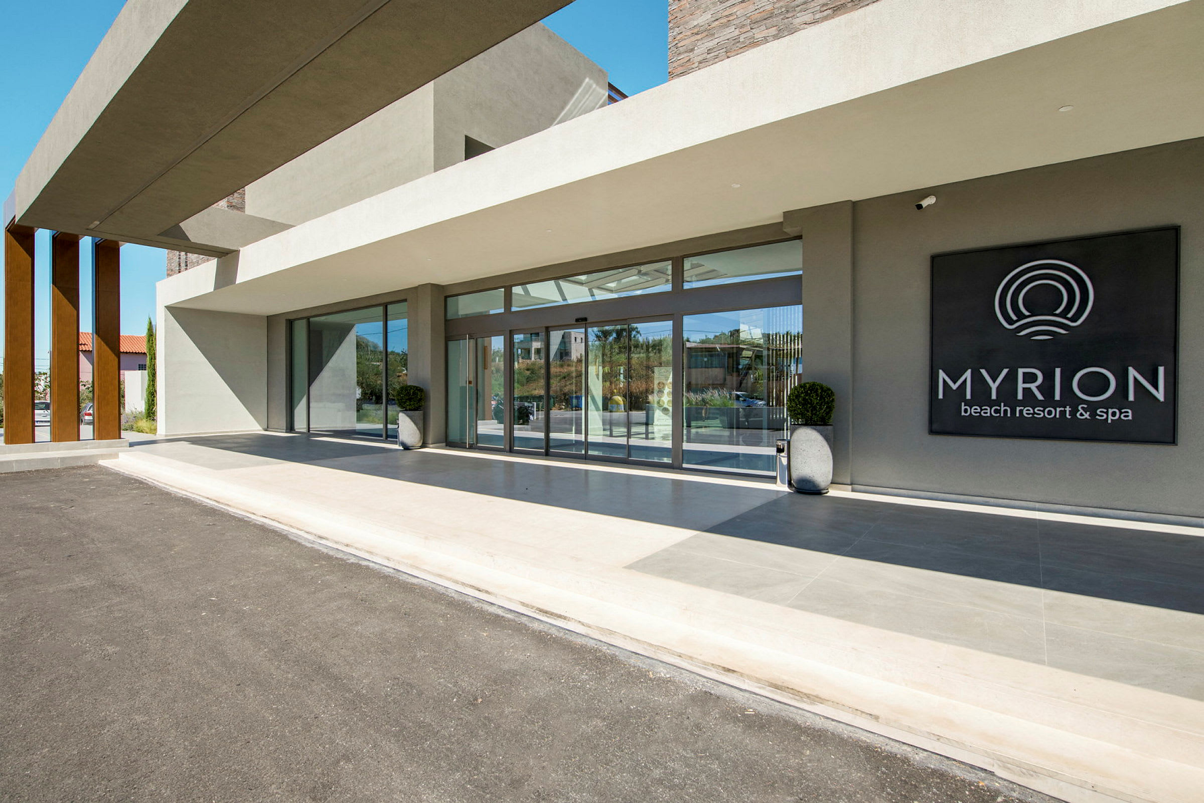 Inngangen til Myrion Beach Resort & Spa med glassvegger og et skilt. (AI-generert tekst)