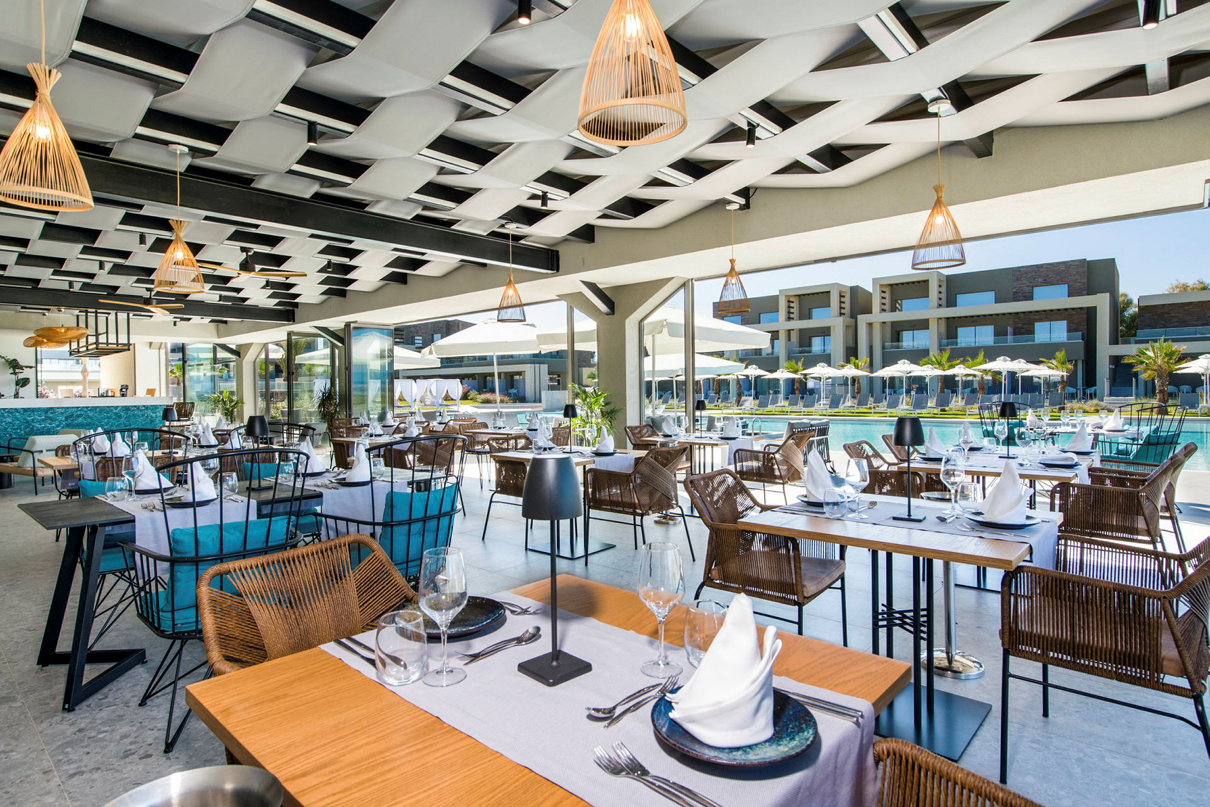 Restaurant med bord og stoler nær et basseng, med resortbygninger i bakgrunnen. (AI-generert tekst)