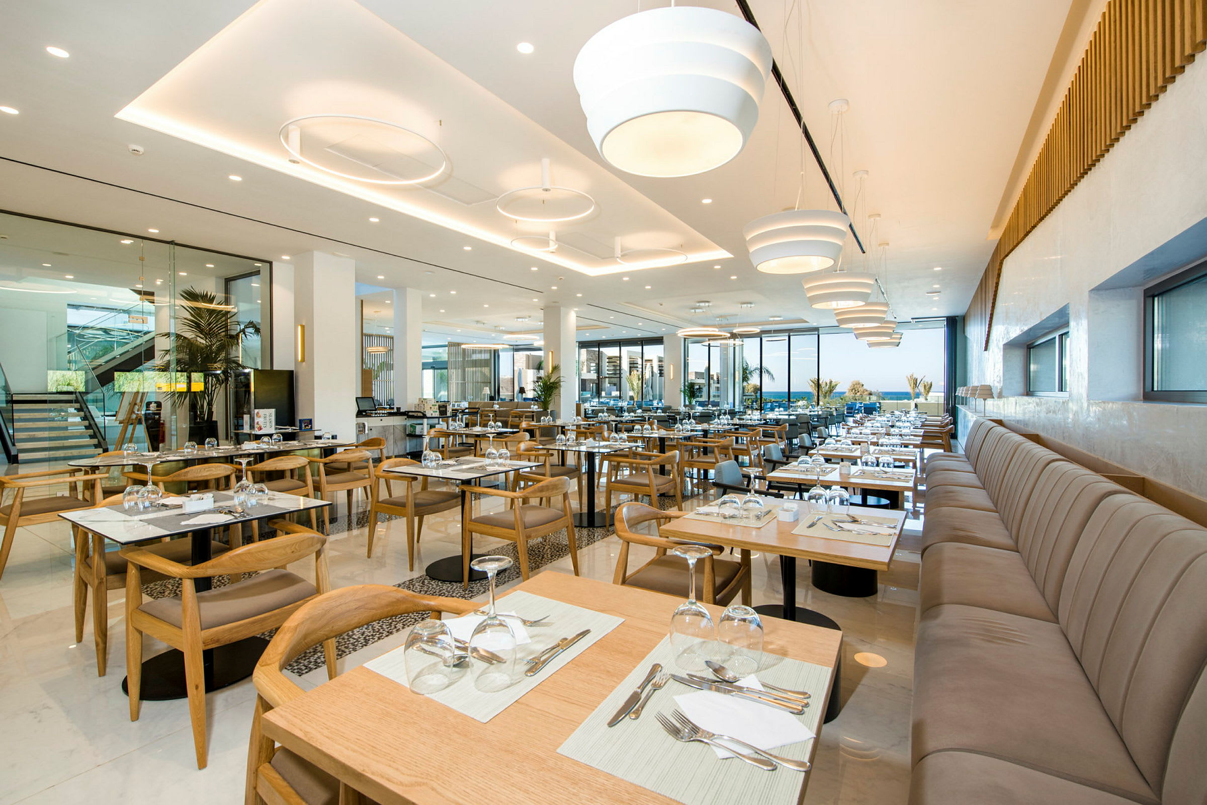 En moderne restaurant med oppstilte bord og stoler samt store vinduer. (AI-generert tekst)