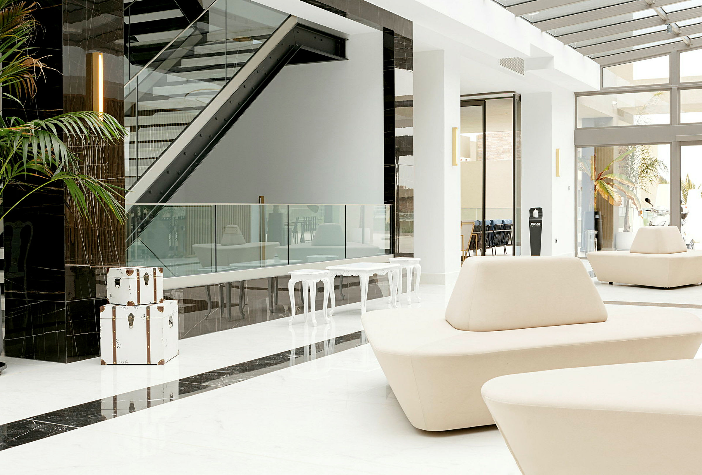 Lys og moderne hotellobby med hvite møbler og glassdetaljer. (AI-generert tekst)