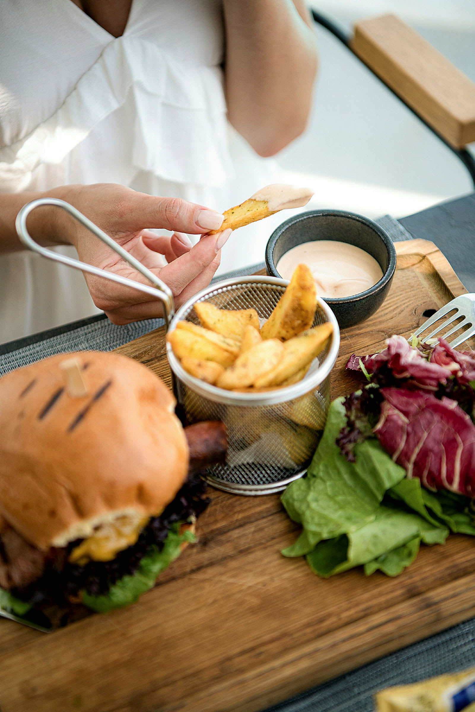 En person dypper en pommes frites i en bolle med saus. (AI-generert tekst)