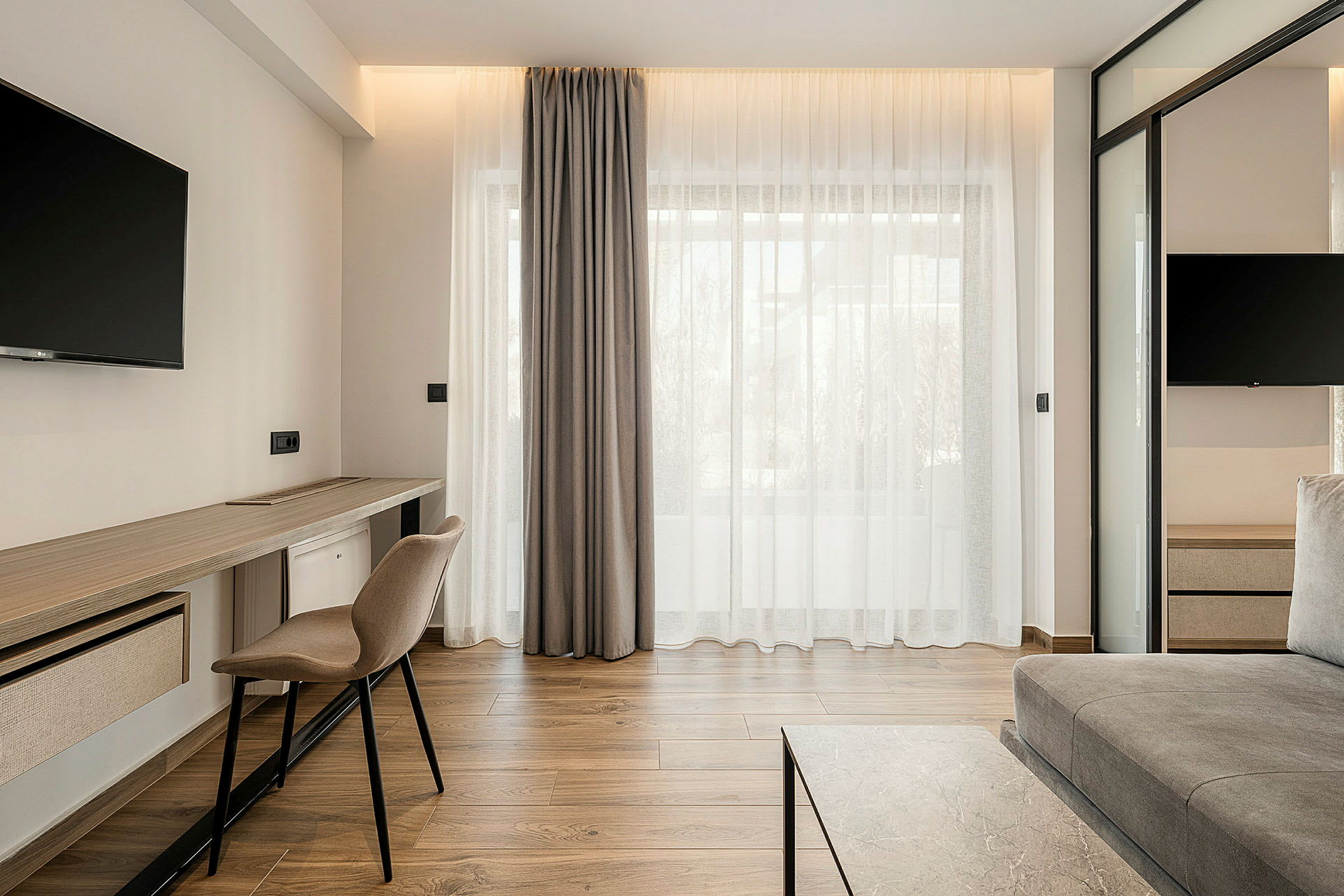 Moderne innredet hotellrom med sittemøbler, skrivebord og TV. (AI-generert tekst)
