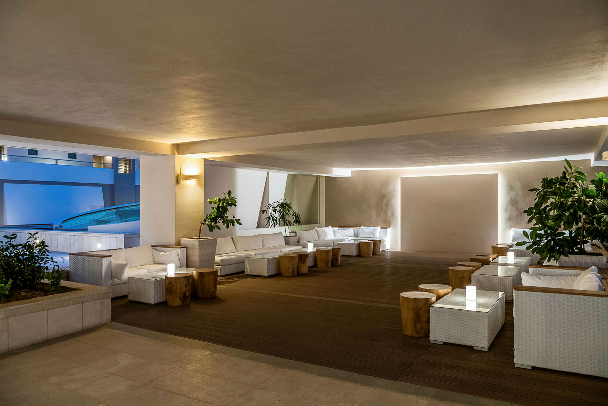 En moderne og elegant lounge med hvite møbler og trebord, omgitt av planter. (AI-generert tekst)