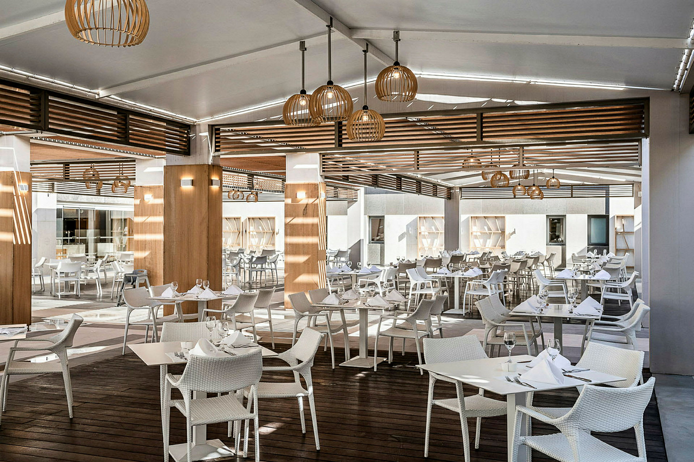 Restaurant med moderne hvite bord og stoler under et overbygd utendørsmiljø. (AI-generert tekst)
