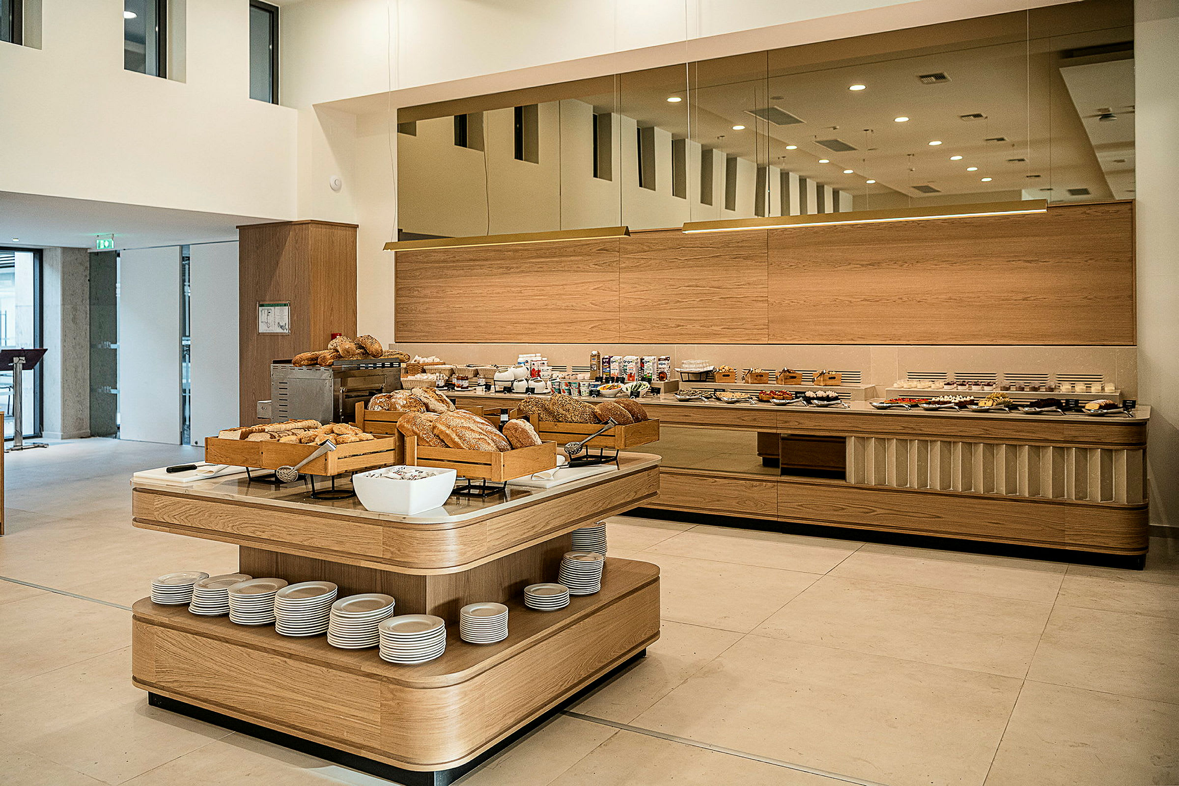 En frokostbuffé med forskjellige brødsorter og tilbehør oppsatt i en lys og moderne spisesal. (AI-generert tekst)