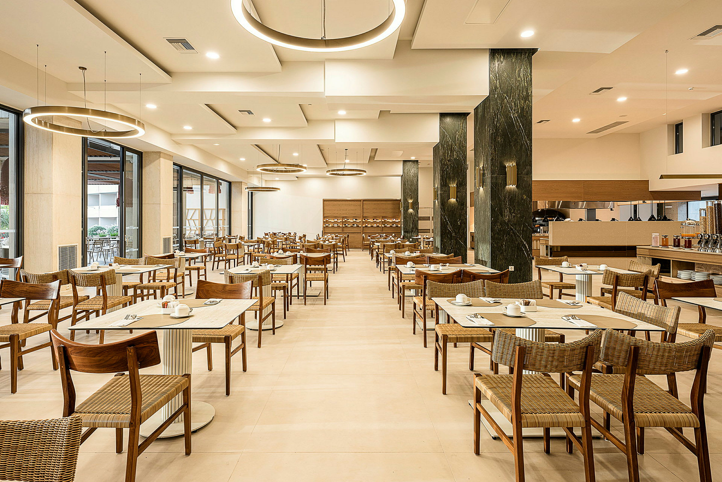 En restaurant med oppdekkede bord og stoler, moderne taklamper og lys innredning. (AI-generert tekst)