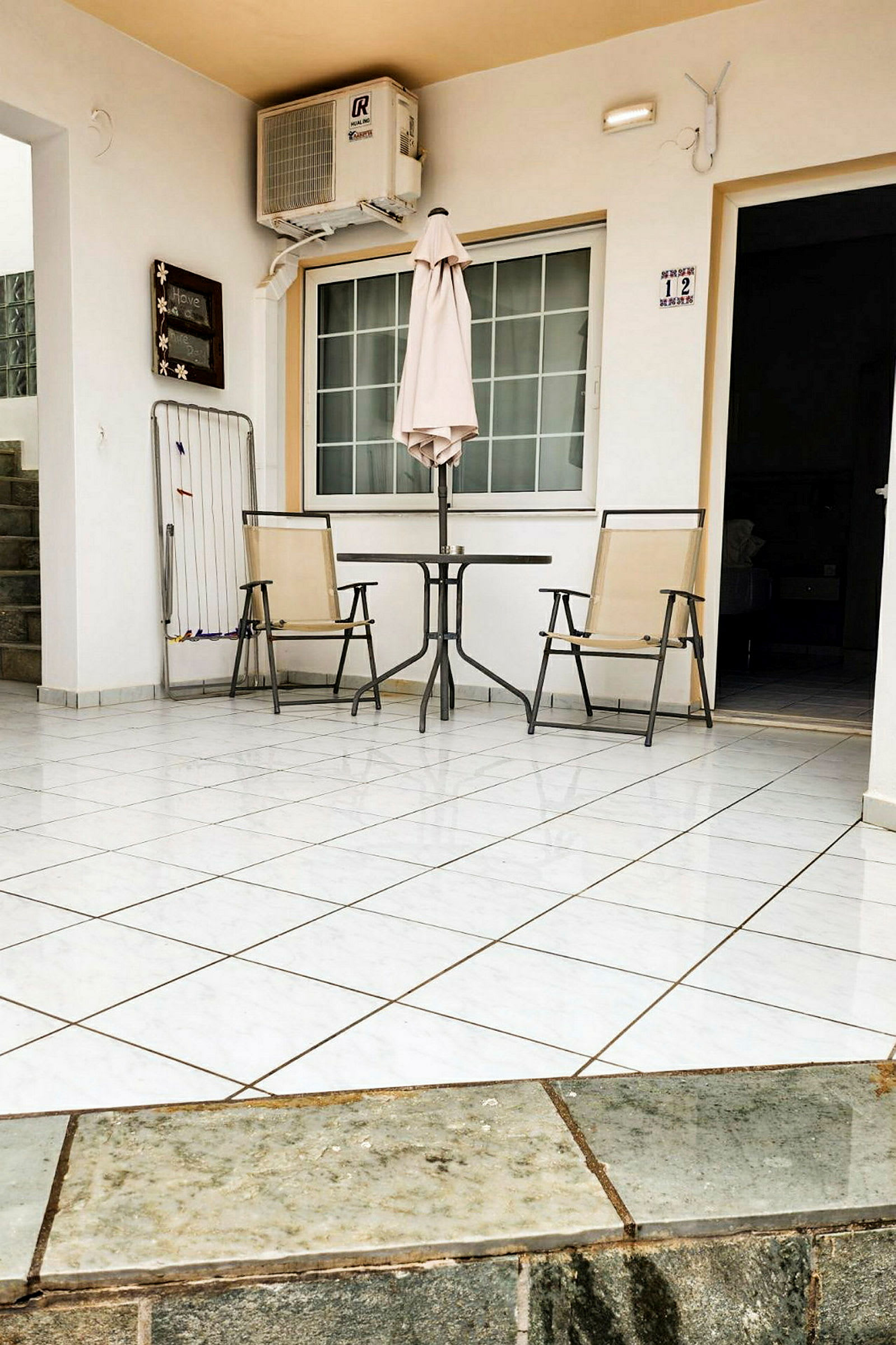 Terrasse med to stoler, et bord og en parasoll foran en hvit bygning. (AI-generert tekst)