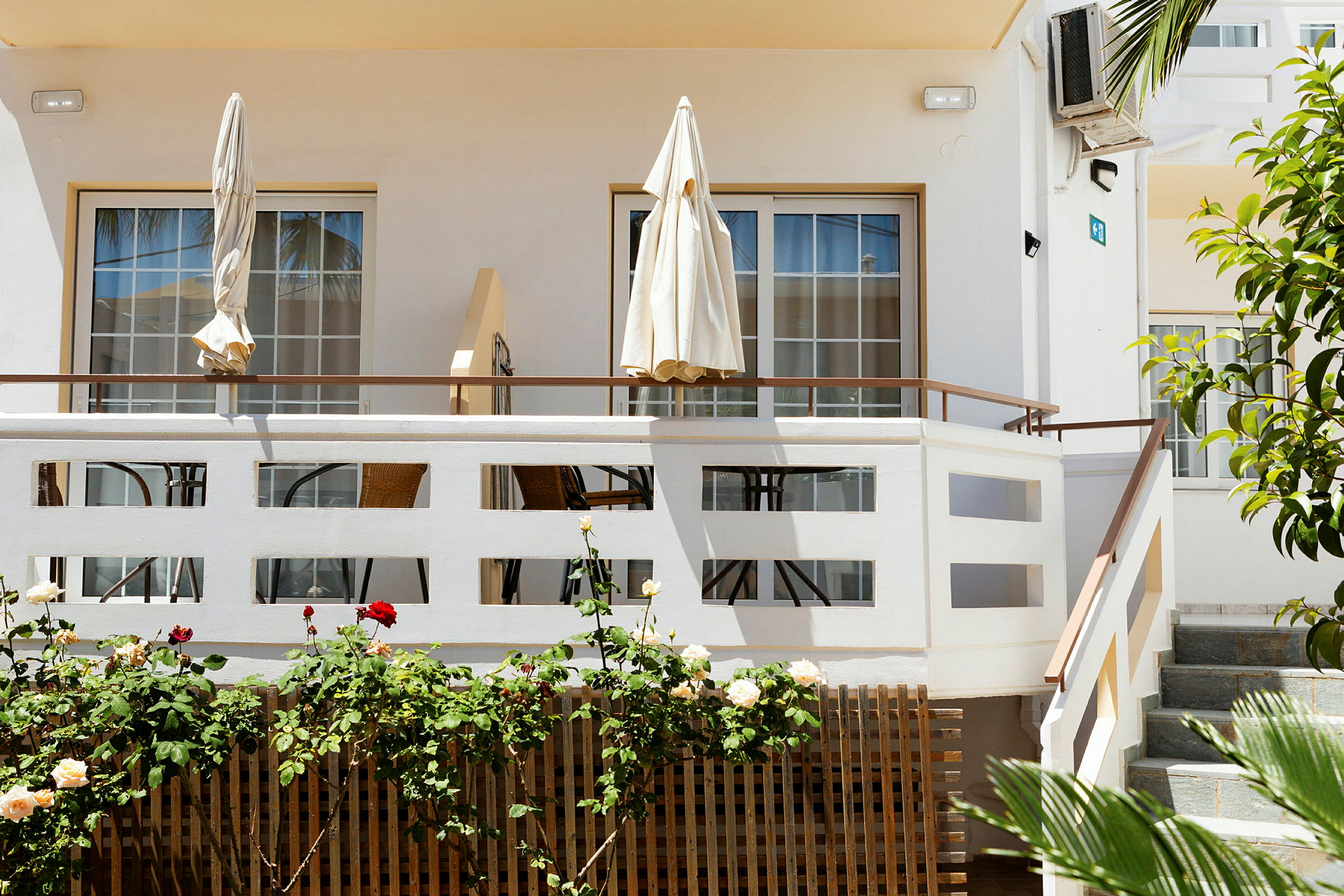 Terrasse med parasoller og utemøbler ved en lys bygning. (AI-generert tekst)