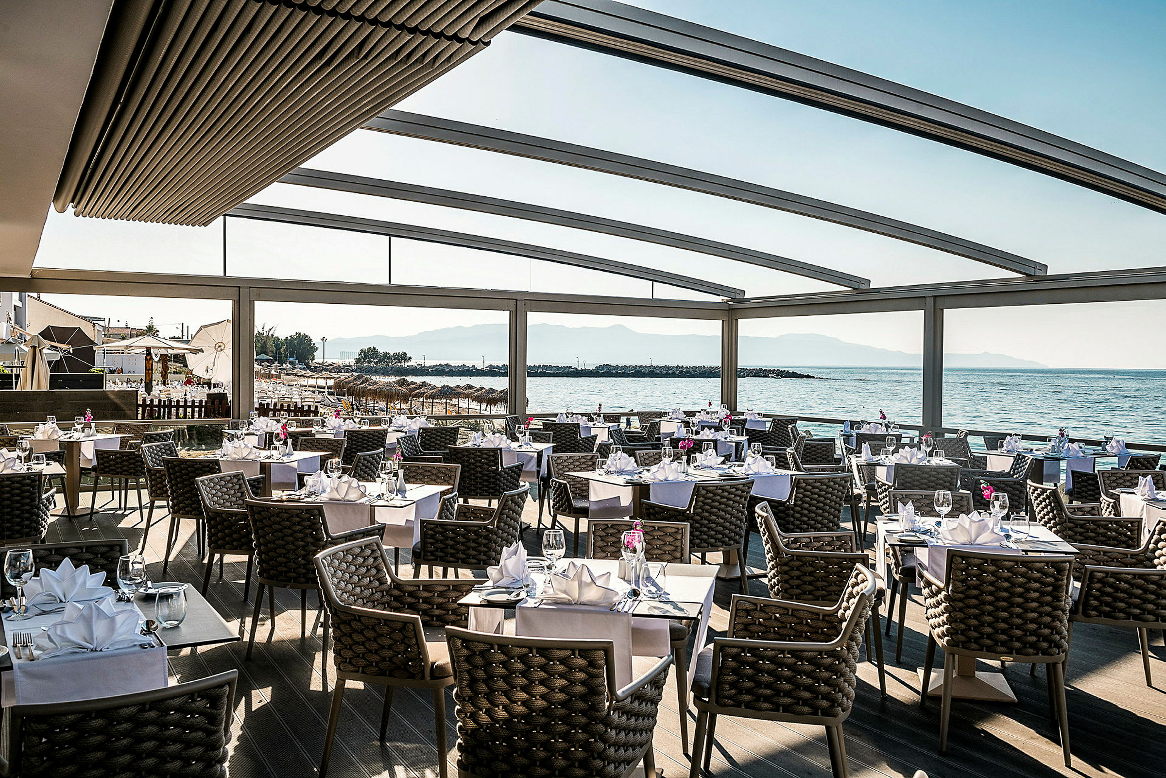 En restaurant med dekkede bord og utsikt over havet. (AI-generert tekst)