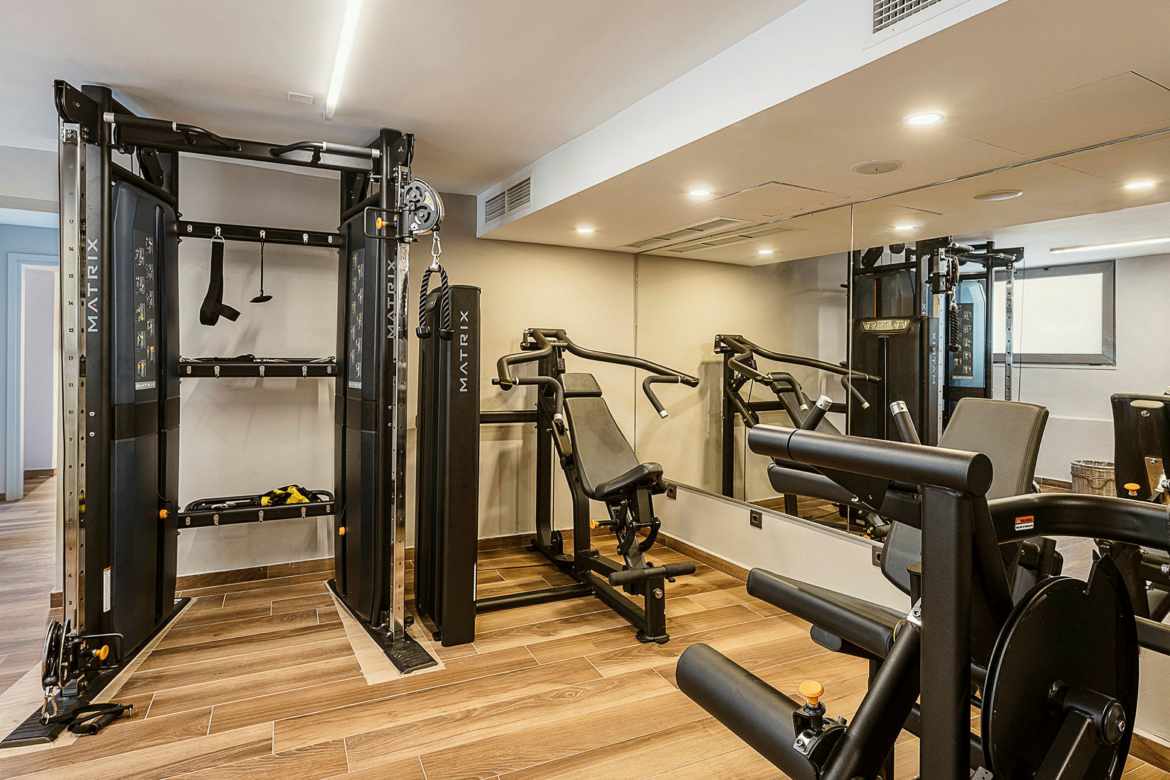 Et treningsrom med treningsutstyr, inkludert en multigym-maskin og en benkpress. (AI-generert tekst)