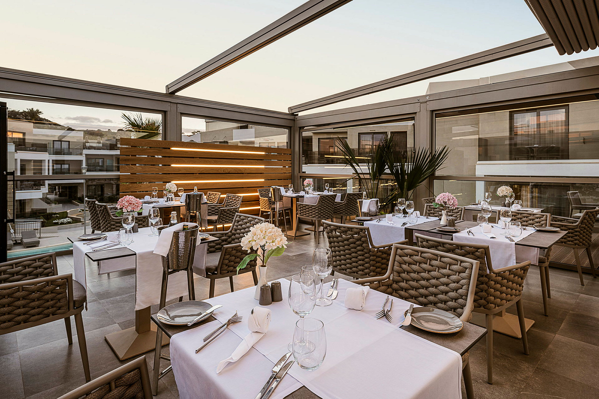 Bilde av en utendørs restaurant med dekkede bord. Innredningen er moderne og elegant. (AI-generert tekst)