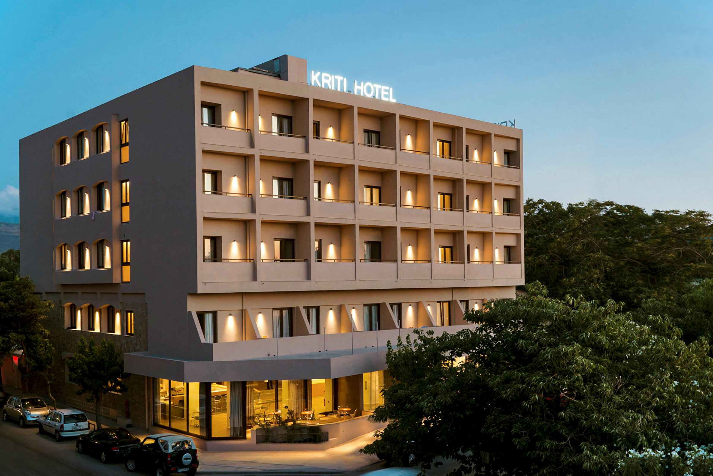 Hotellbygning med flere etasjer, belysning og parkering ved inngangen. (AI-generert tekst)