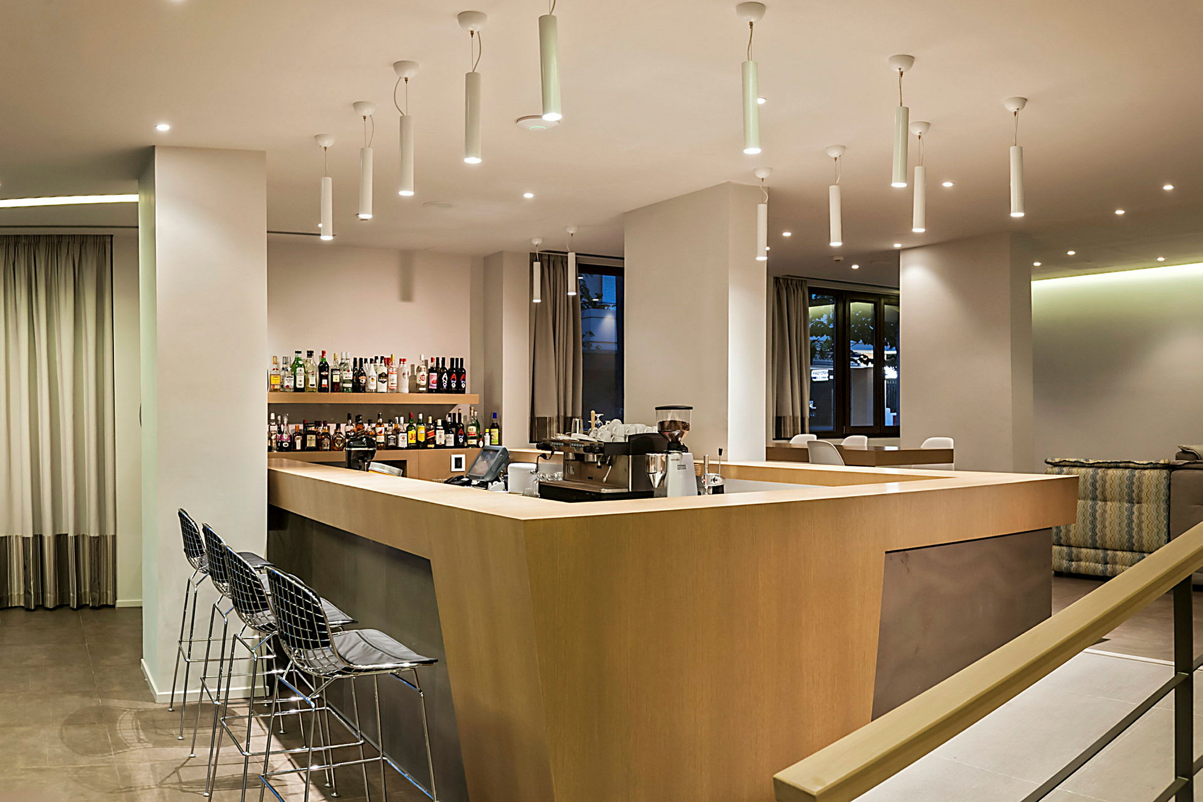 Bilde av en moderne hotellbar med tredisk, stoler og hyller med flasker. (AI-generert tekst)