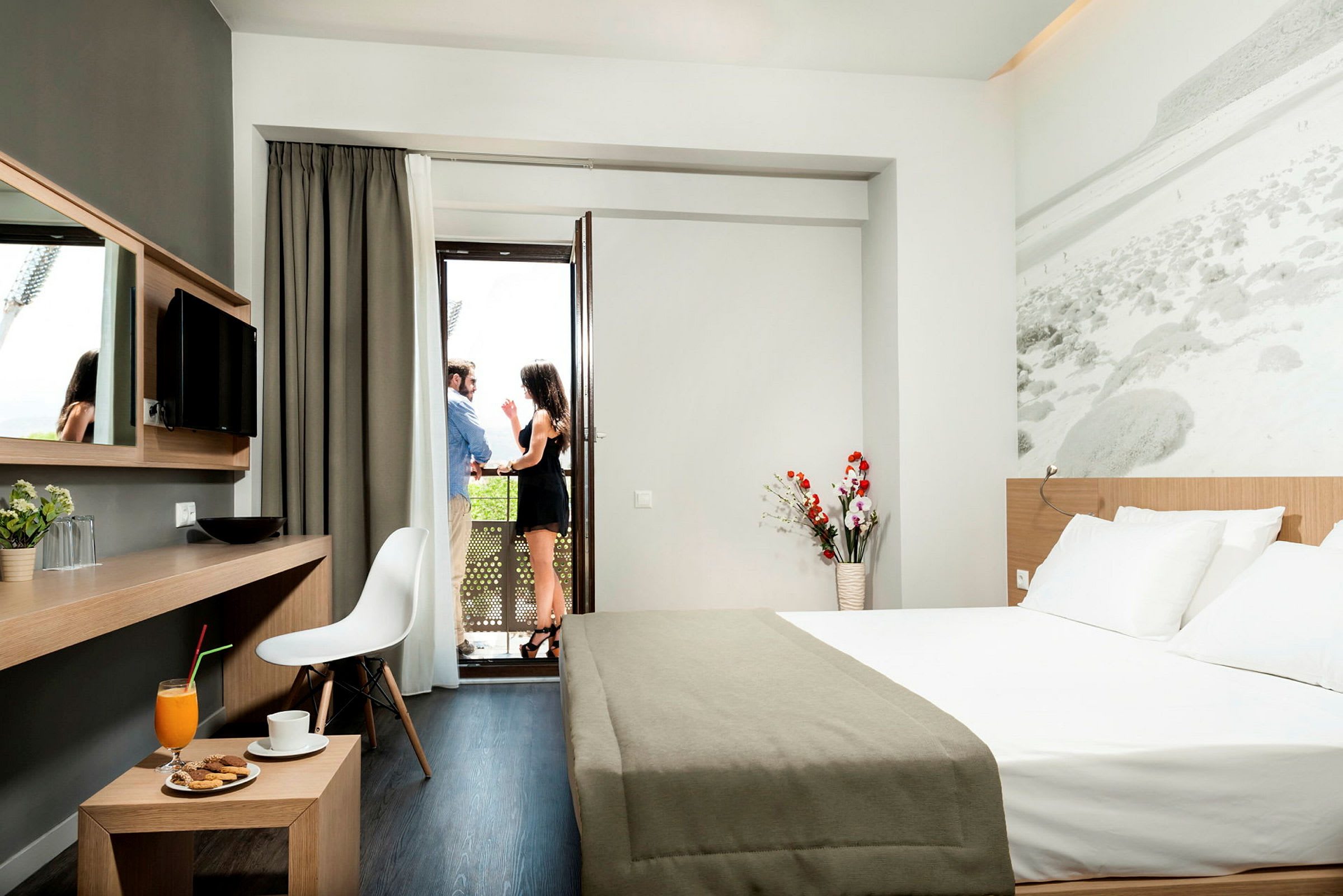 Moderne hotellrom med dobbeltseng, skrivebord og utsikt mot en balkong. (AI-generert tekst)