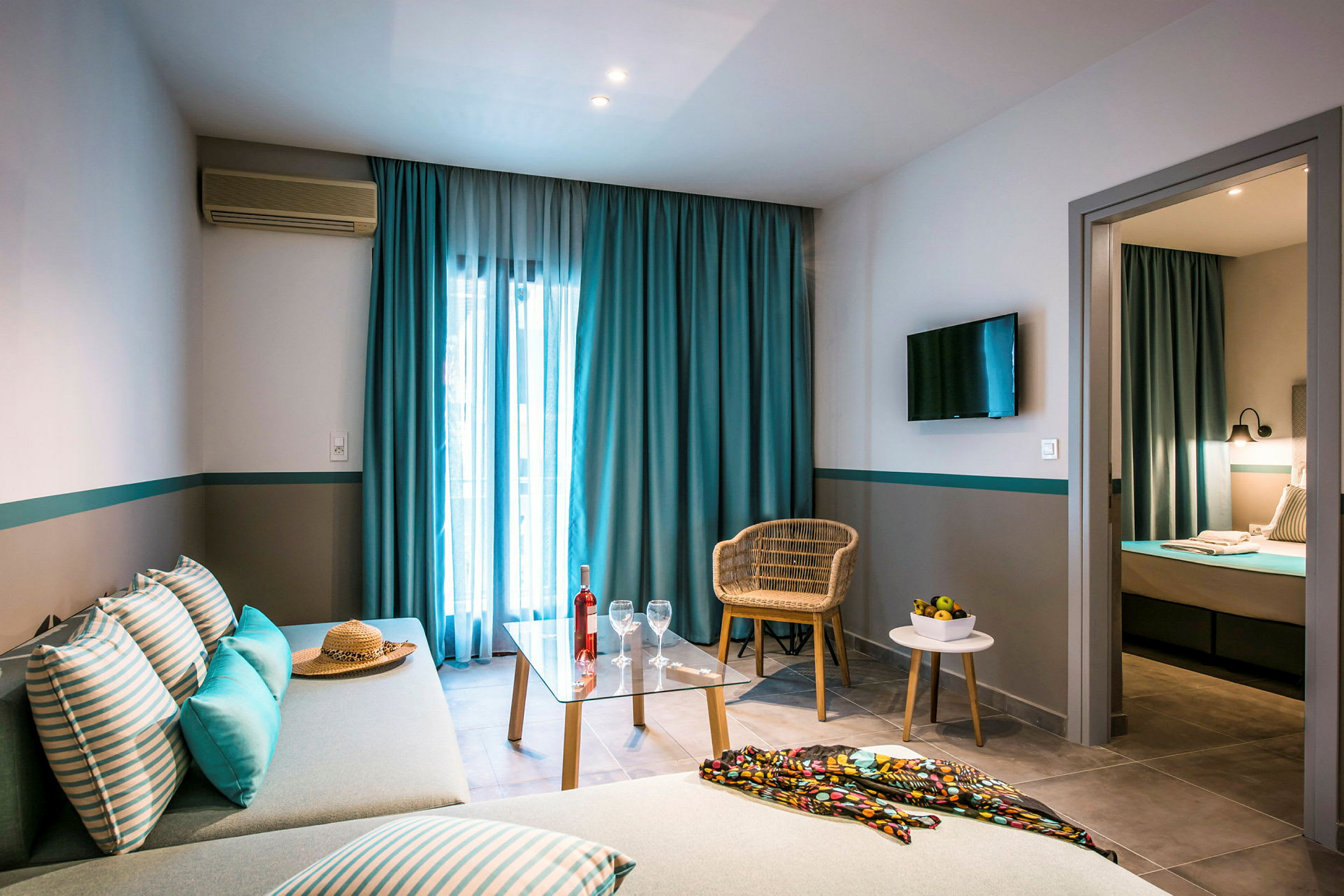 Bilde av et hotellrom med sofa, bord og stol, samt seng i et separat soverom. (AI-generert tekst)