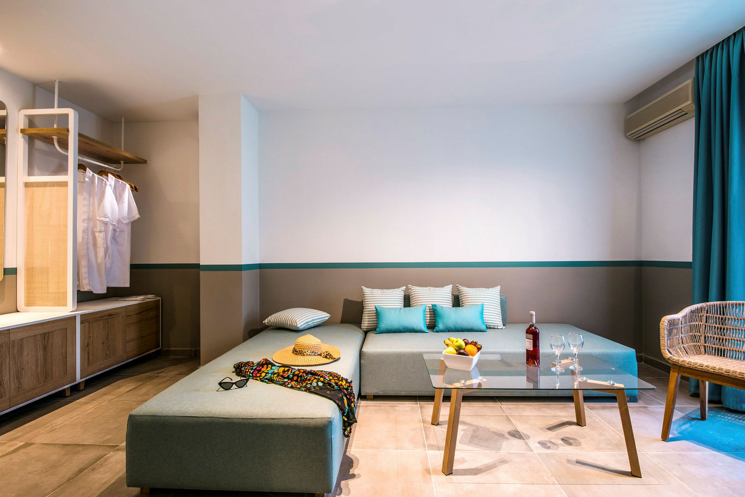 Moderne hotellrom med hjørnesofa, klart glassbord og avslappet innredning. (AI-generert tekst)