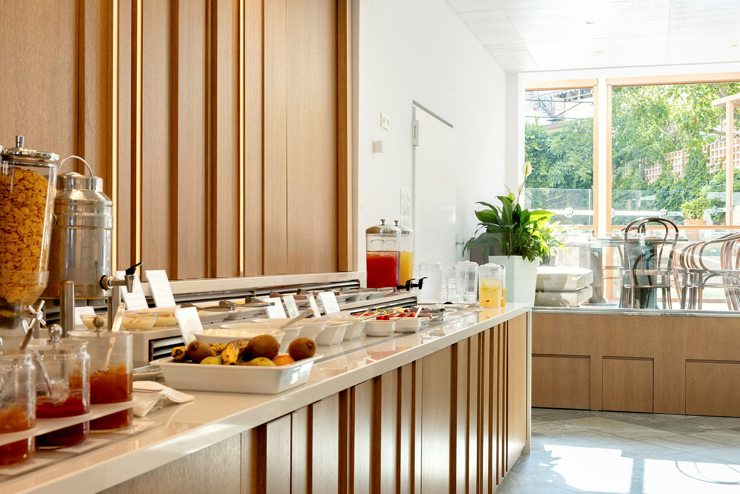 Frokostbuffé med forskjellige alternativer og drikkevarer, samt sitteplasser i bakgrunnen. (AI-generert tekst)