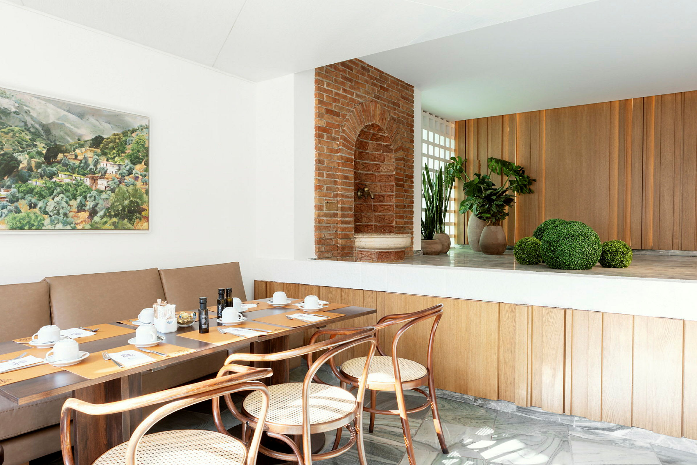 Et moderne restaurantmiljø med bord dekket til et måltid, kunst på veggen og planter i bakgrunnen. (AI-generert tekst)