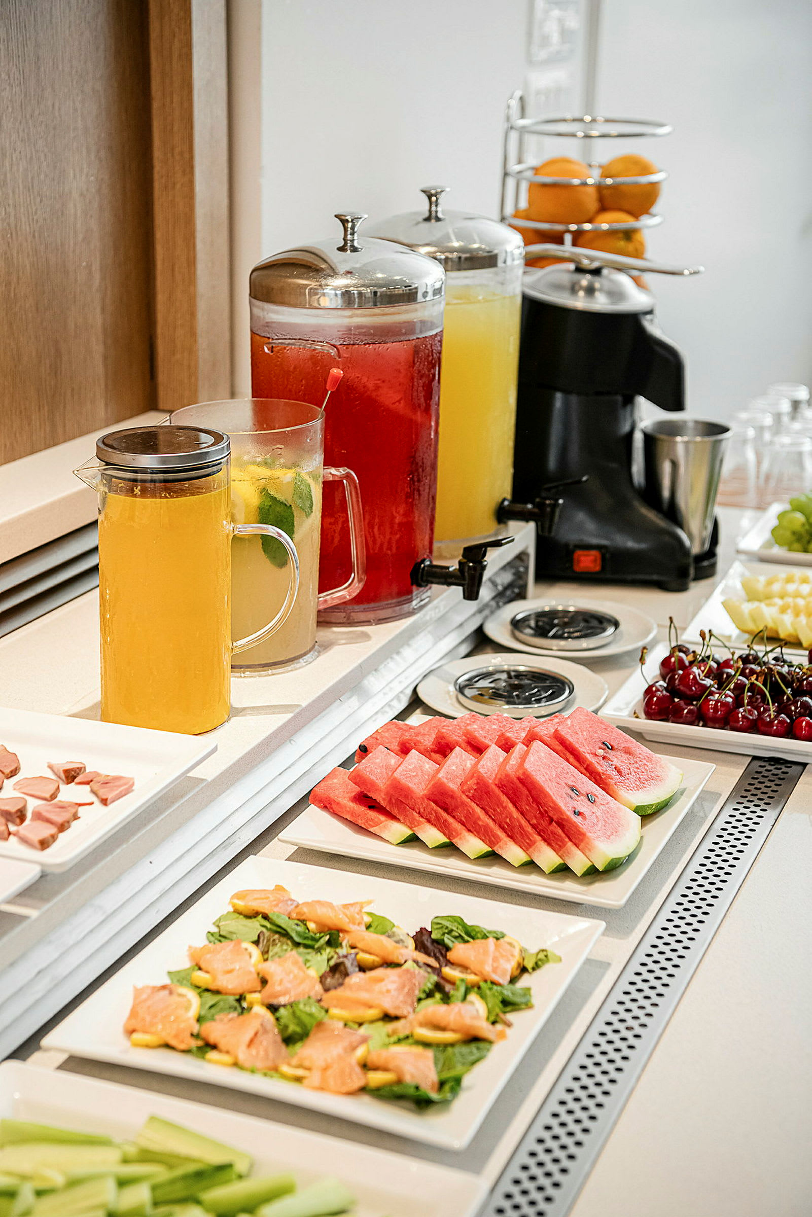 Buffet med fruktskiver, salatretter og karafler med drikke. (AI-generert tekst)