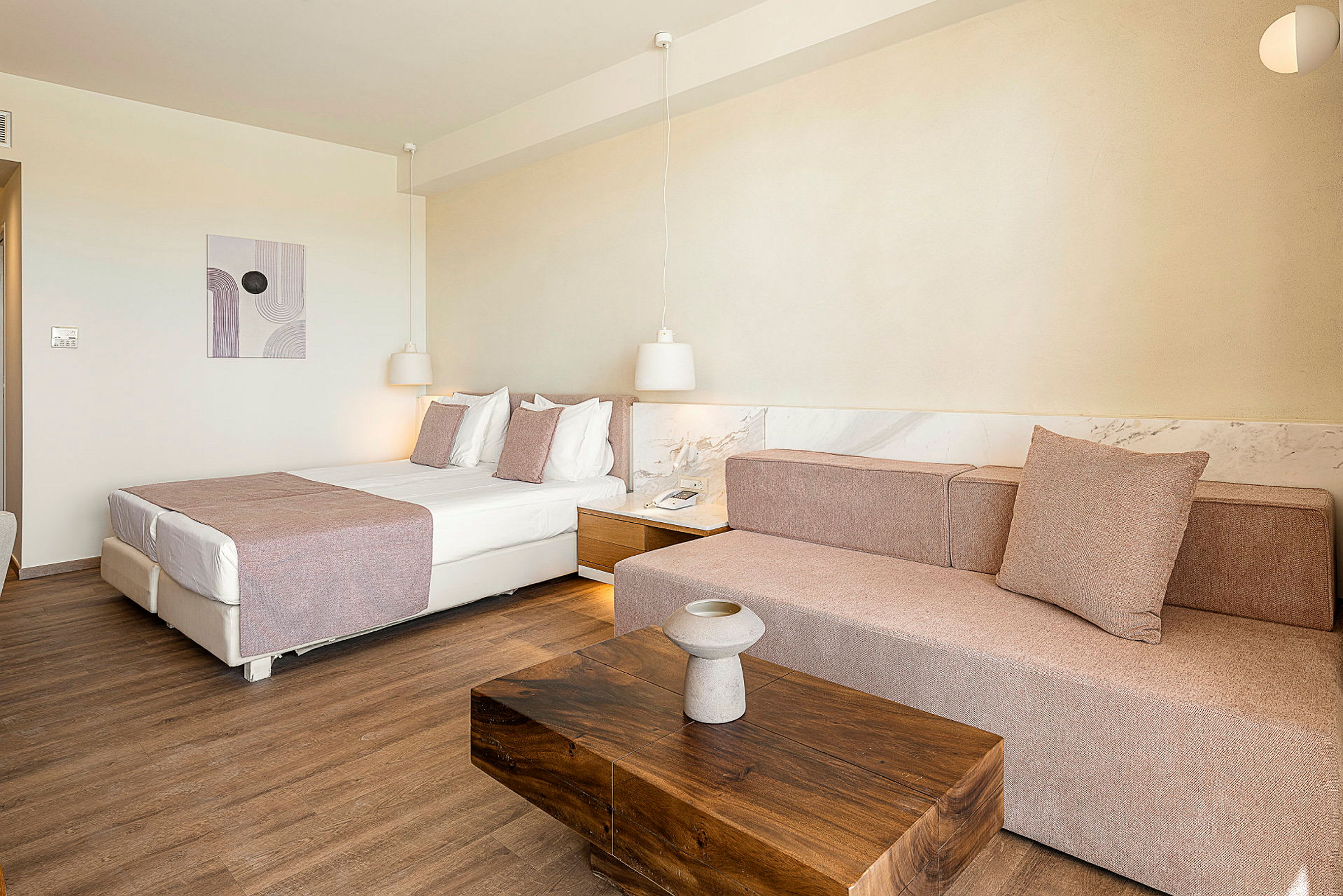 Et hotellrom med en seng, en sofa og et trebord. (AI-generert tekst)