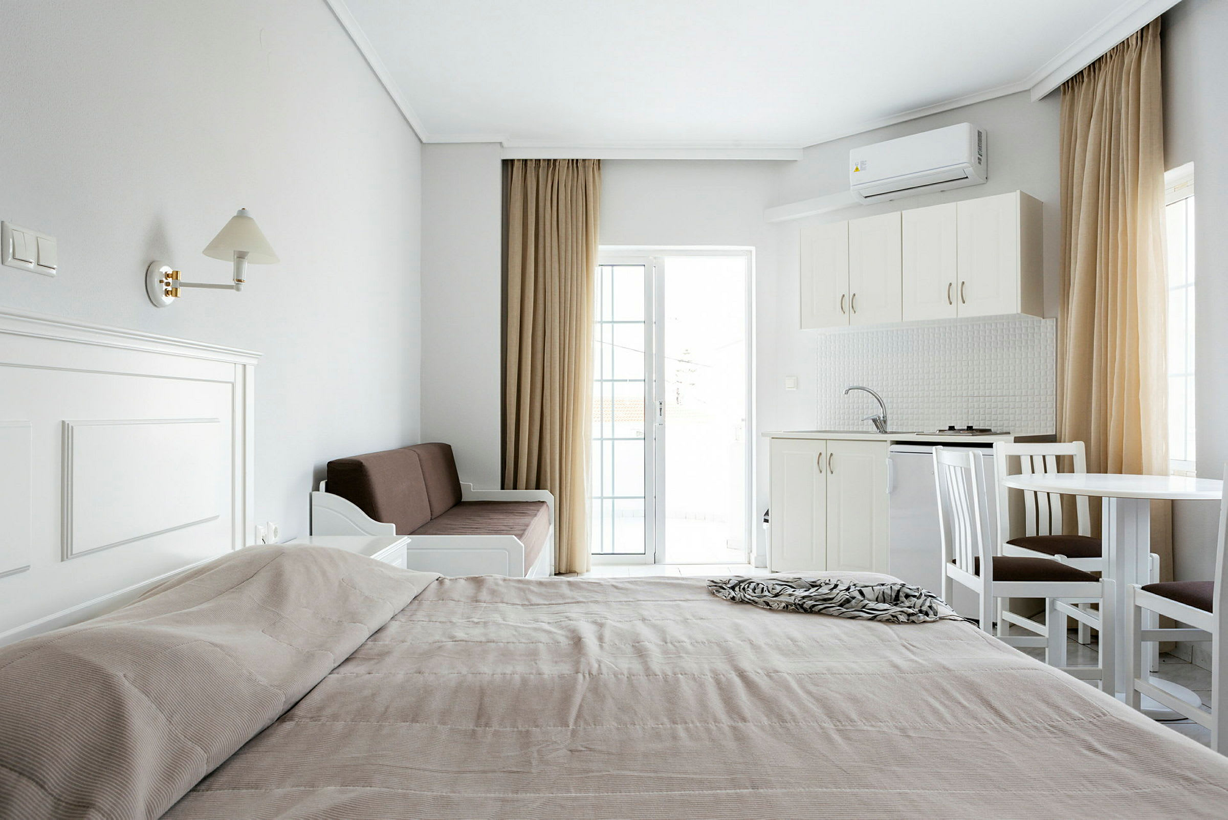 En oversikt over et hotellrom med en seng, sofa, kjøkken og spisebord. (AI-generert tekst)