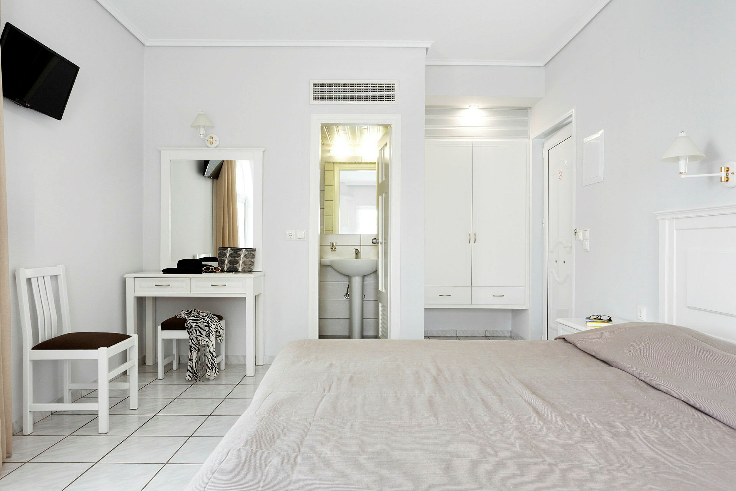 Et lyst hotellrom med skrivebord, stol og seng, samt en garderobe og et bad. (AI-generert tekst)