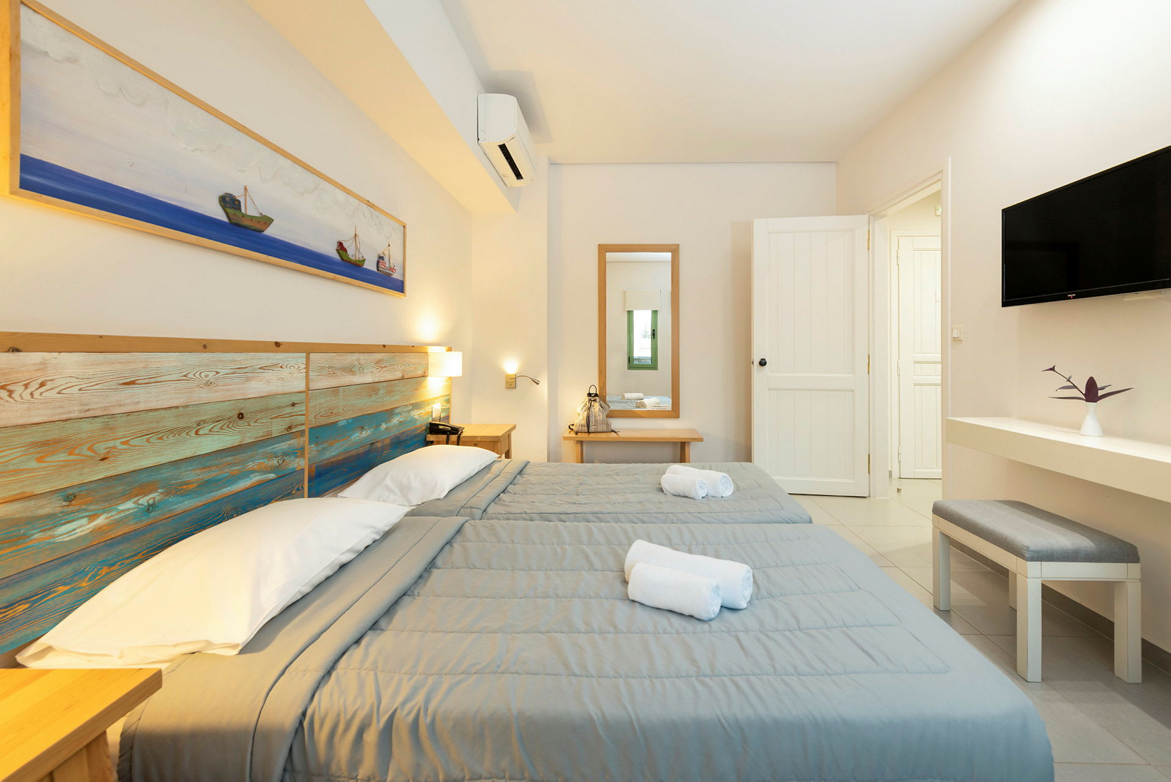 To enkeltsenger med grå sengetepper i et lyst hotellrom. (AI-generert tekst)