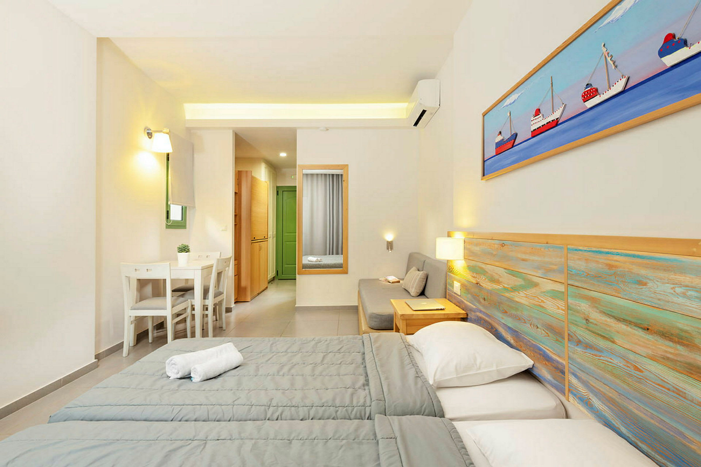 Et hotellrom med to senger, en sittegruppe og en liten spiseplass. (AI-generert tekst)