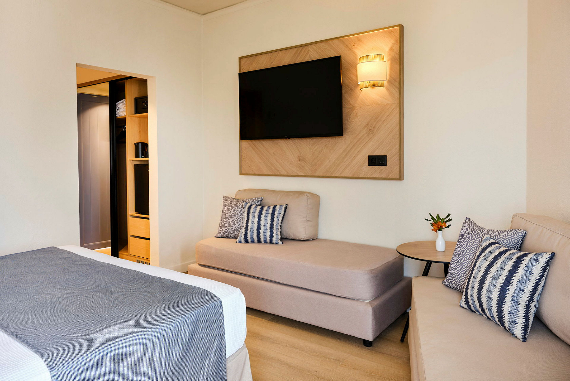 Et hotellrom med sofa, seng og TV på veggen. (AI-generert tekst)