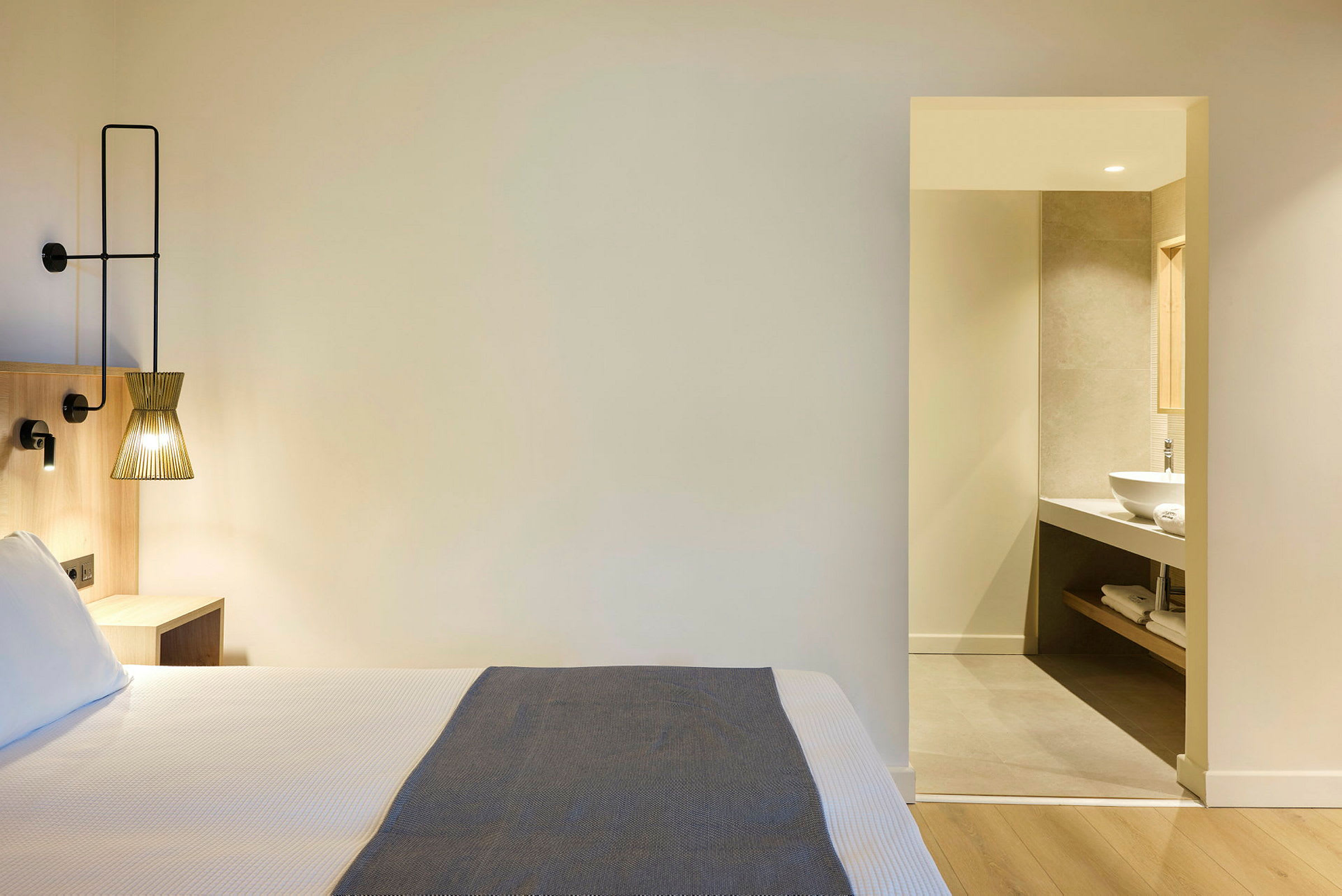 Hotellrom med seng og en åpning til bad. (AI-generert tekst)
