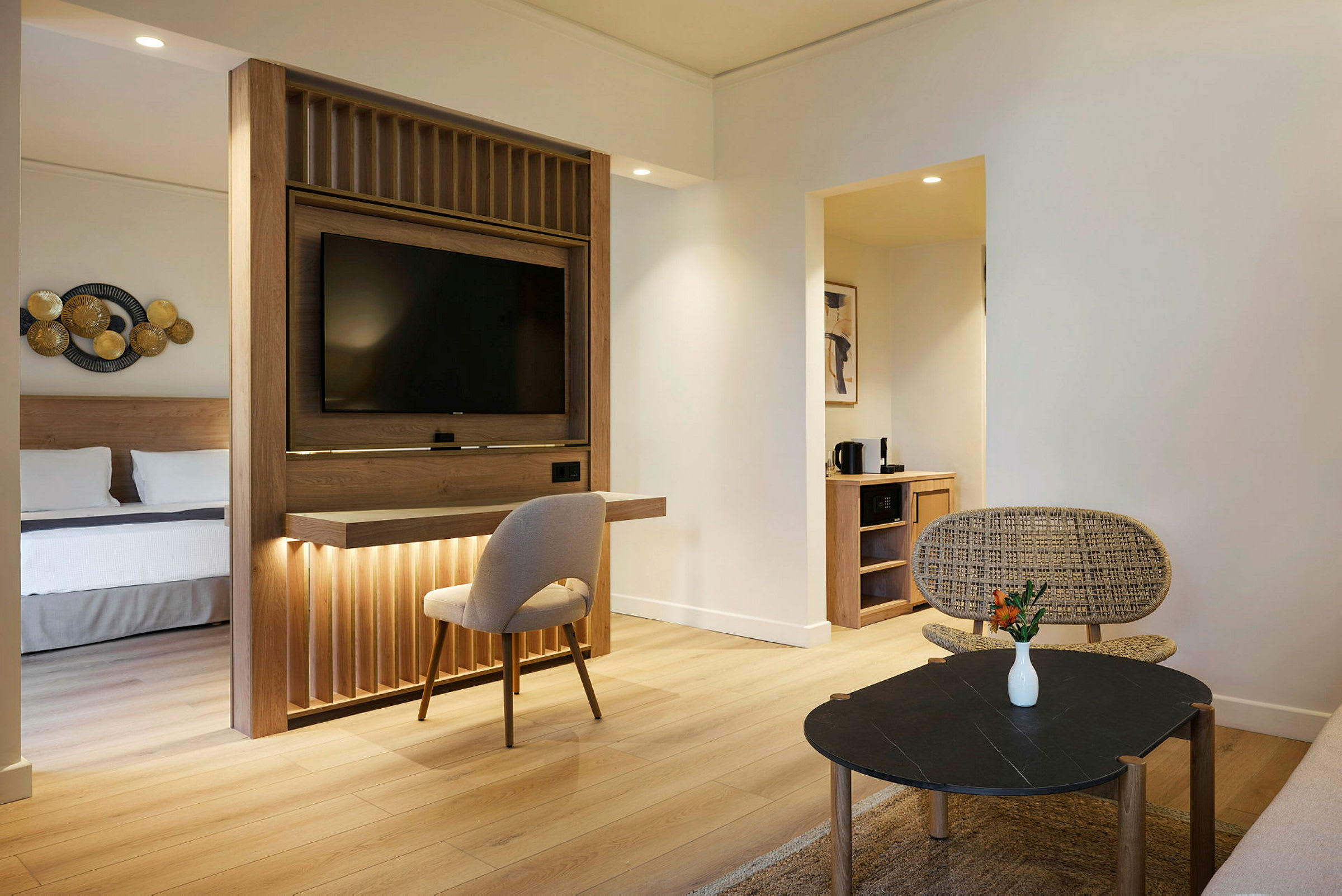 Hotellrom med moderne innredning, separat soveområde og stue med sittemøbler og bord. (AI-generert tekst)