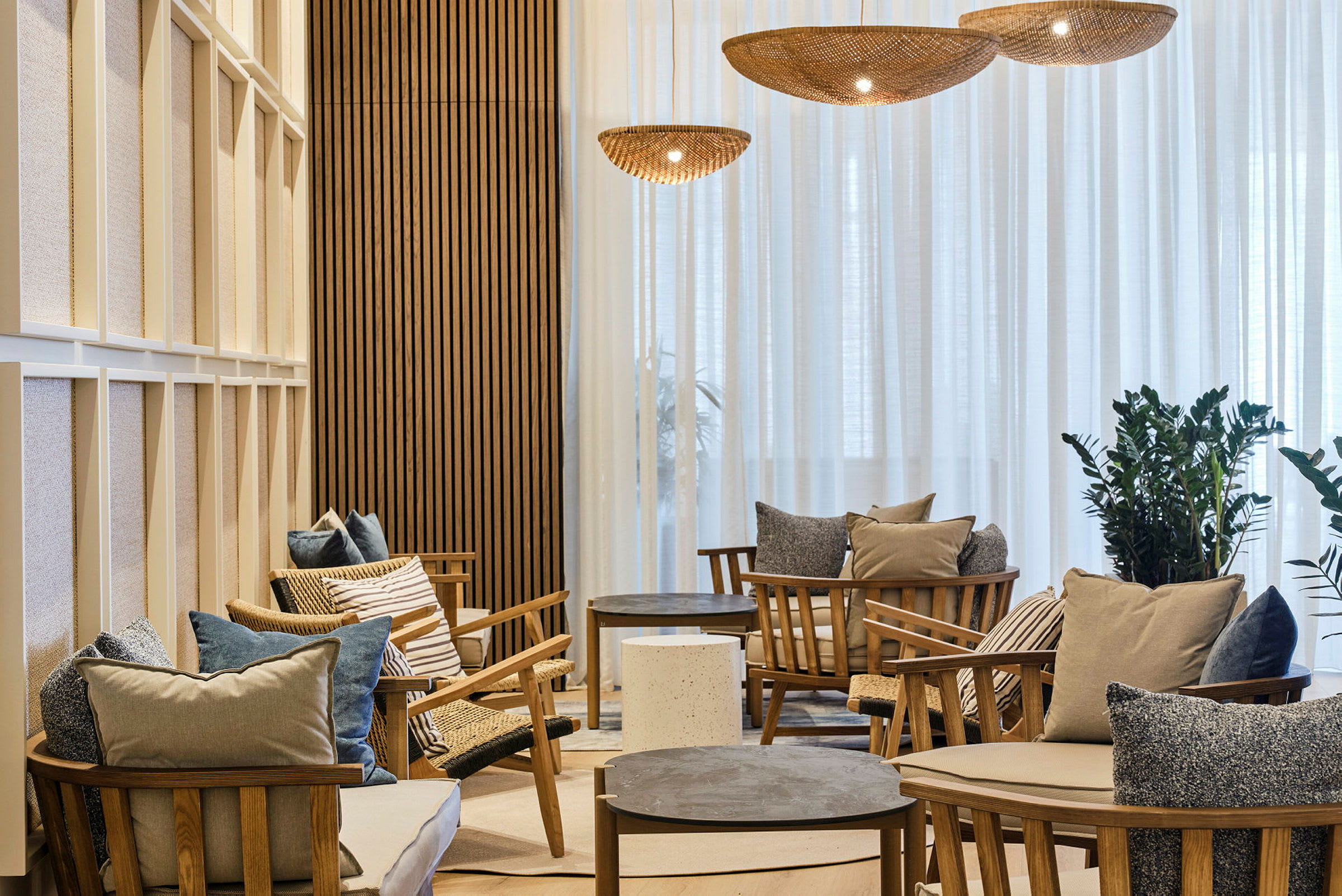 En stilfull lounge med trelenestoler, puter og lave bord. (AI-generert tekst)
