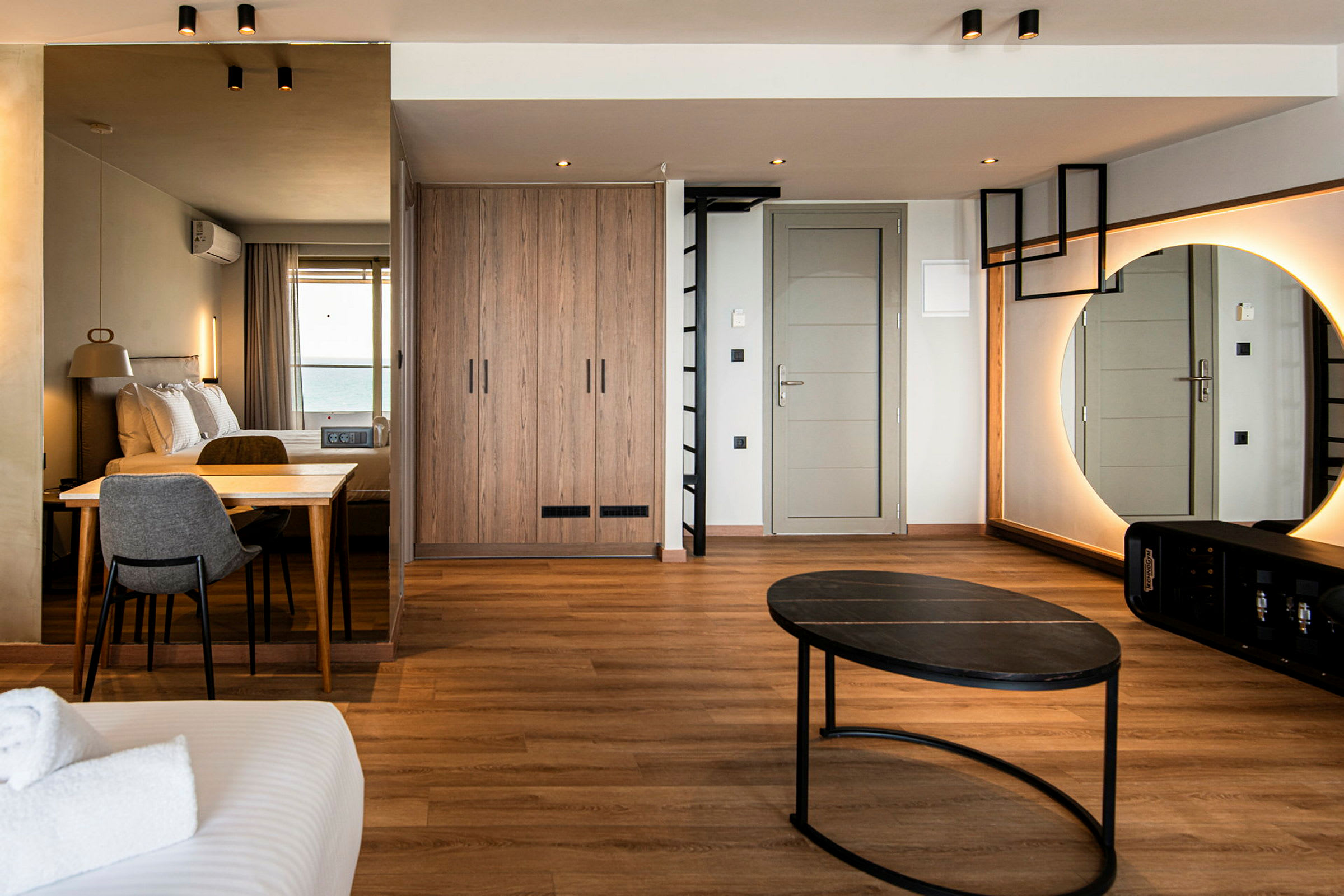 Hotellrom med moderne innredning, inkludert seng, bord, stol, speil og garderobe. (AI-generert tekst)