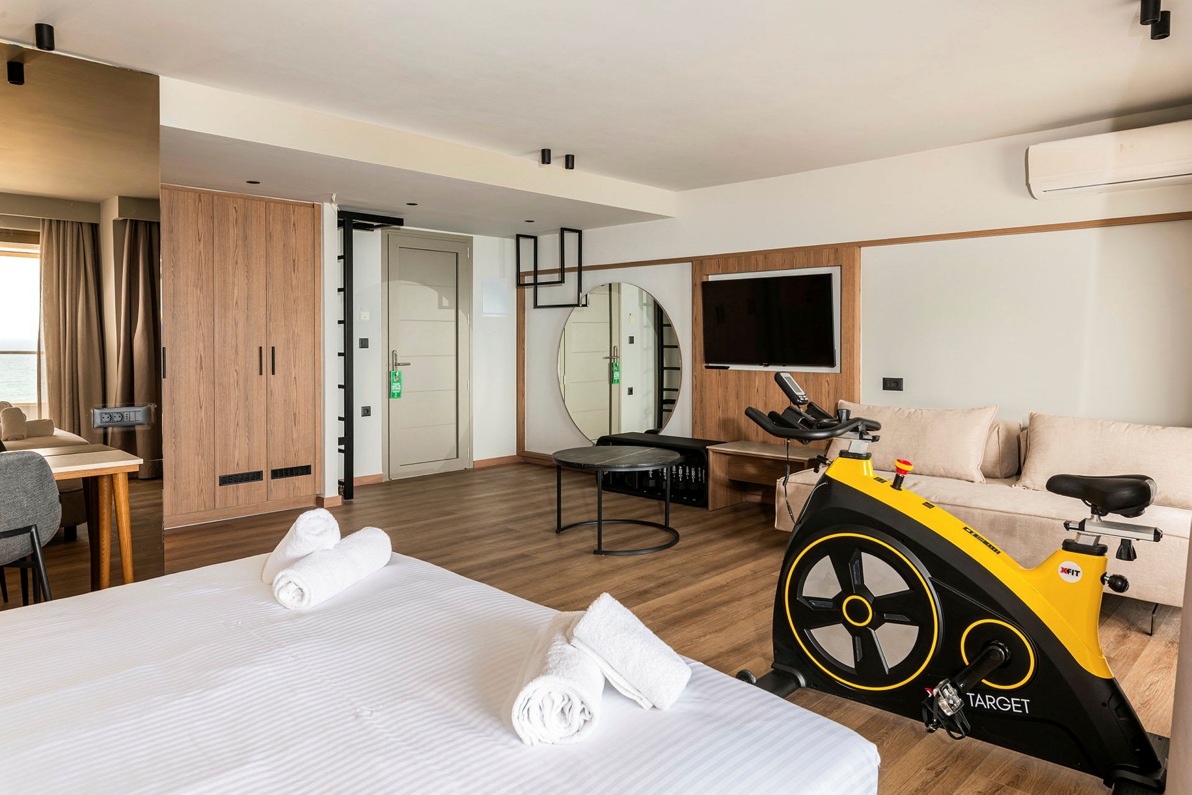 Et moderne hotellrom med seng, sittegruppe, trimsykkel og TV. (AI-generert tekst)