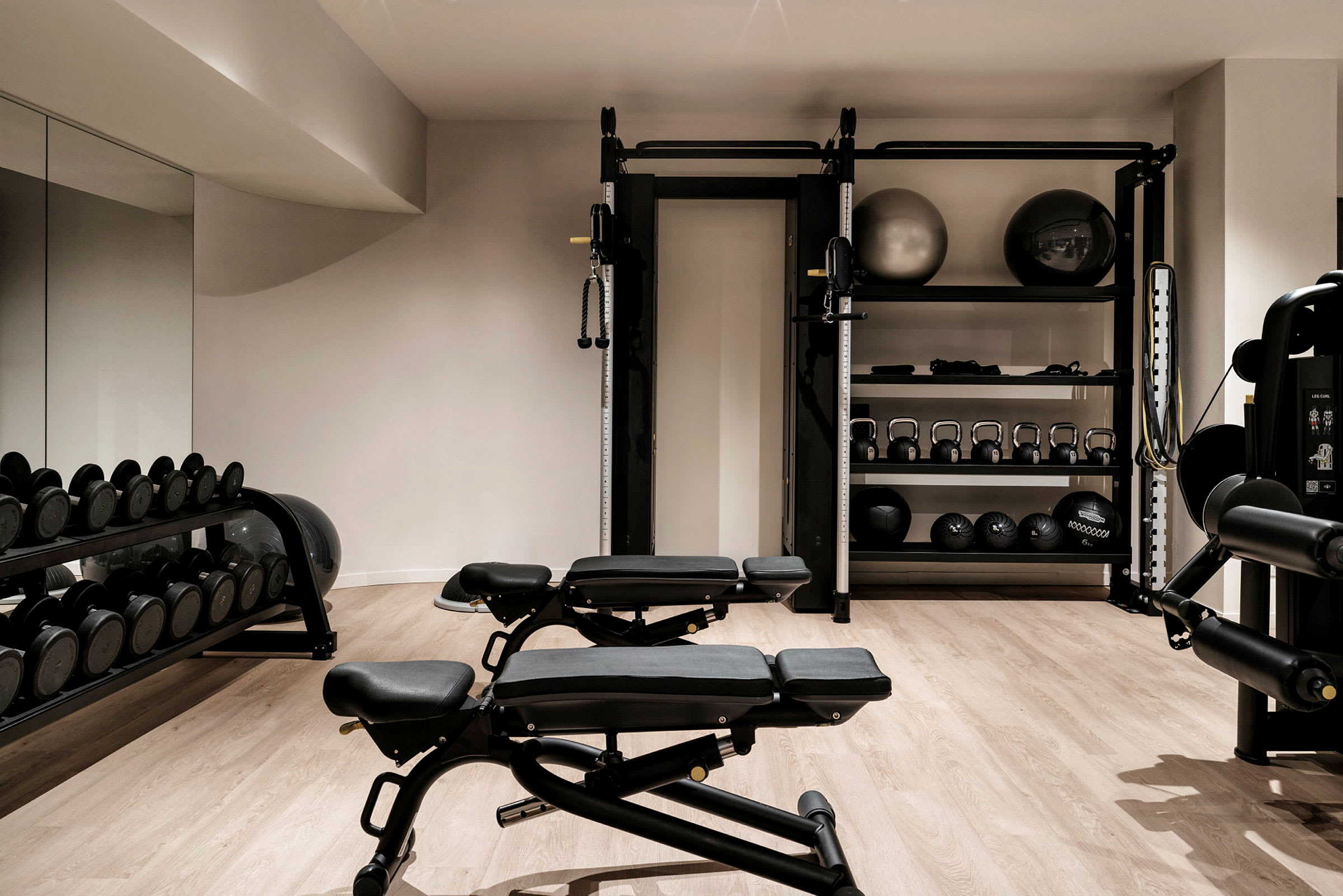 Et treningsrom med utstyr som benker, frie vekter og pilatesballer. (AI-generert tekst)